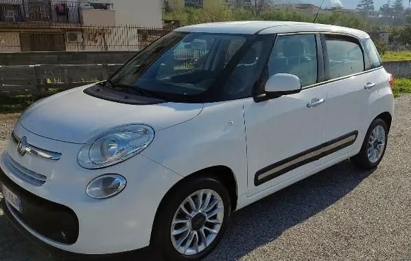 Un'auto bianca è parcheggiata su una strada sterrata di fronte a un edificio.