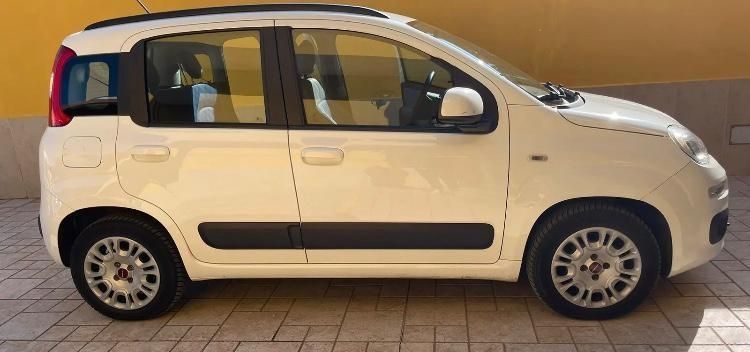Un'auto bianca è parcheggiata davanti a un muro giallo
