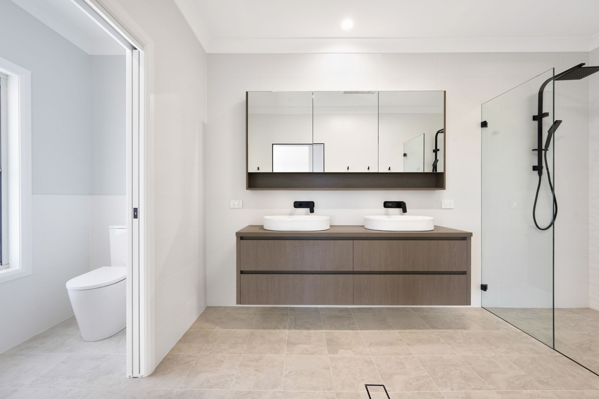 A bathroom with two sinks , a toilet and a walk in shower.