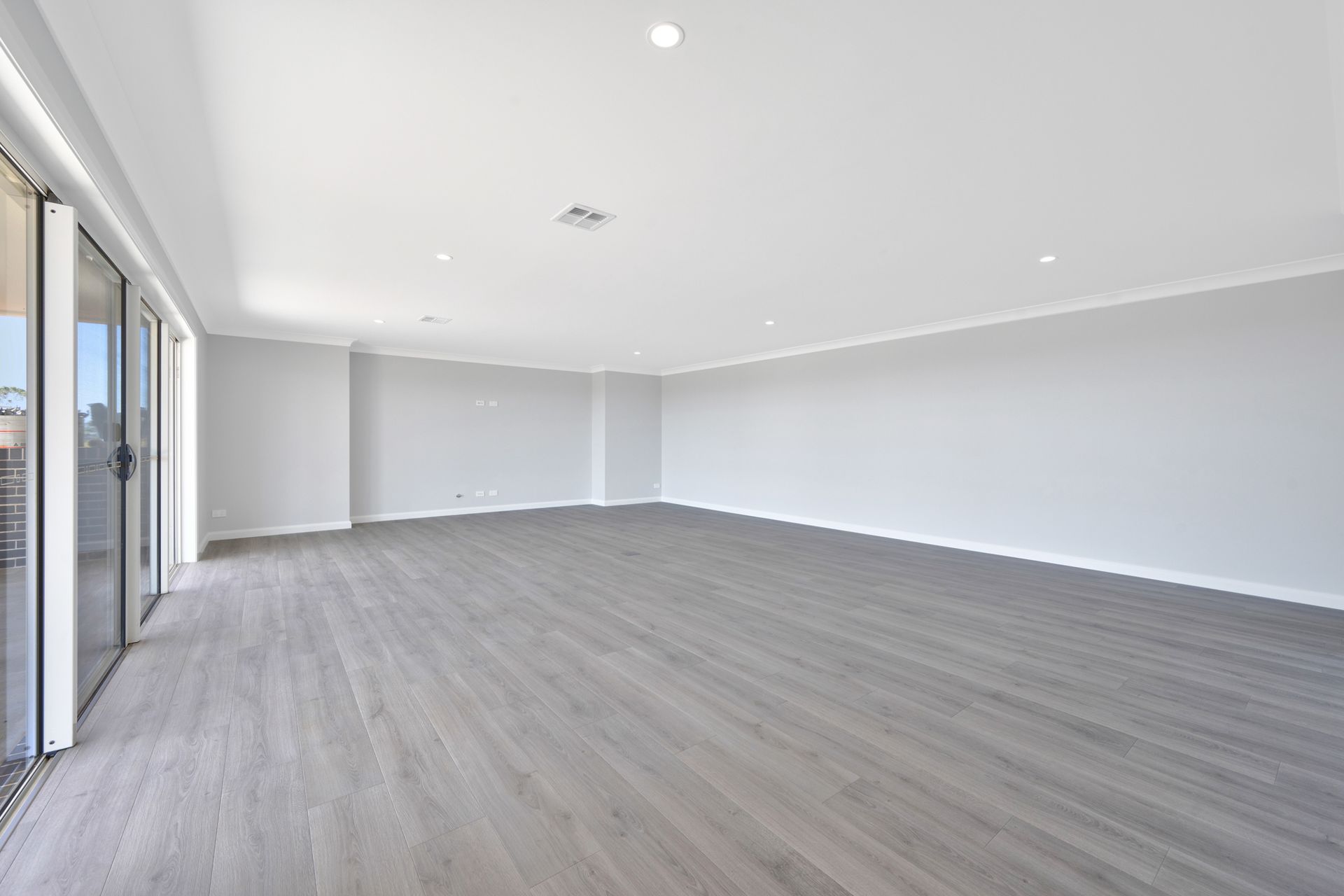An empty living room with hardwood floors and white walls.
