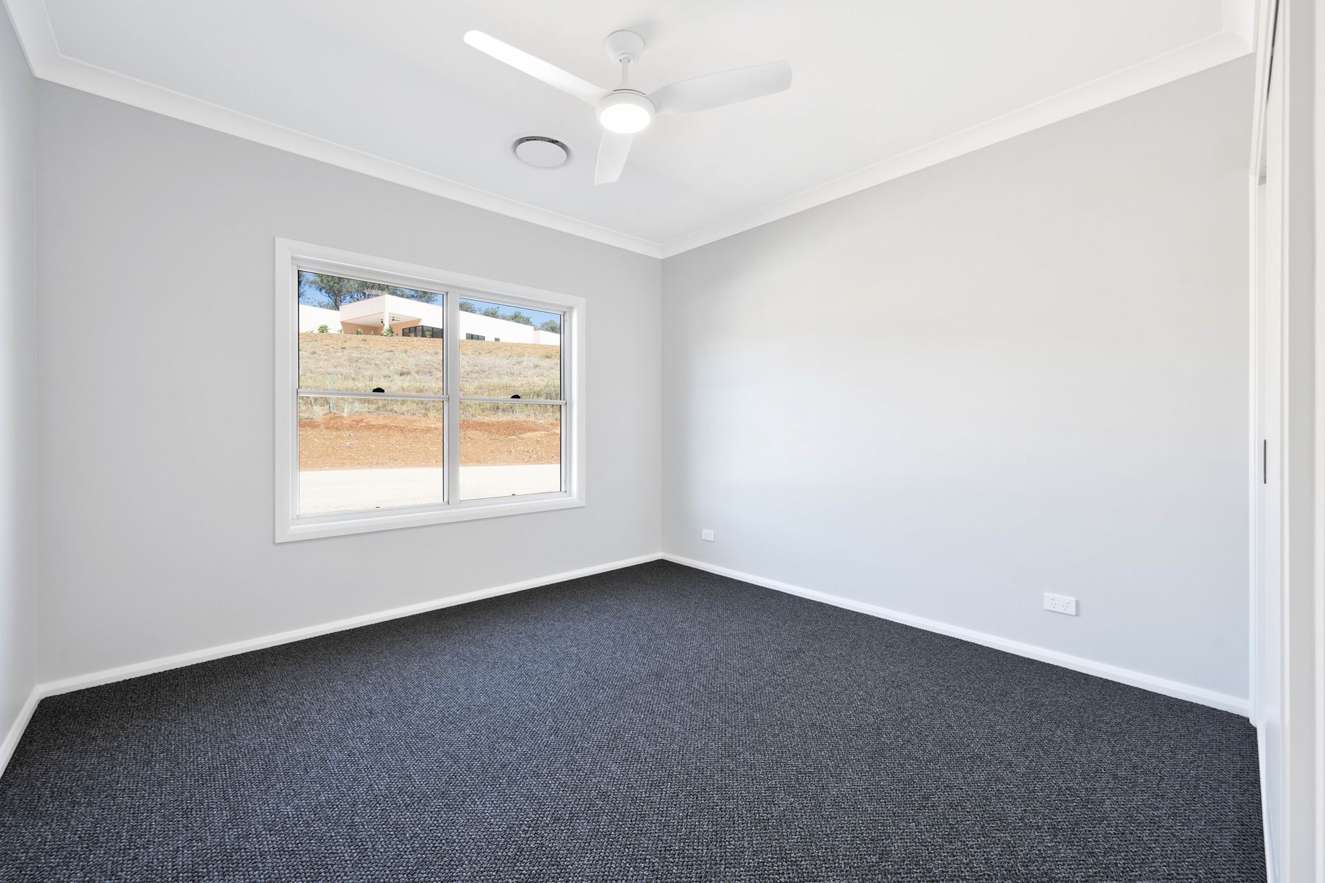 An empty bedroom with a ceiling fan and a window.