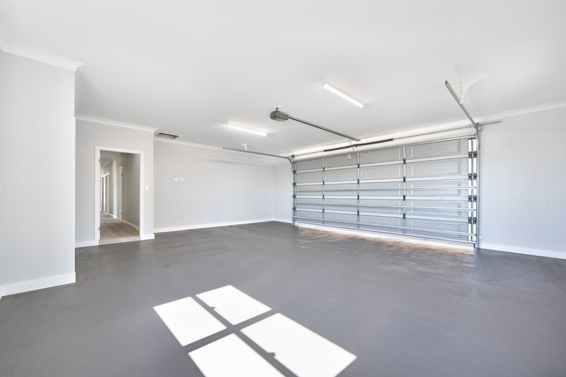 An empty garage with a garage door open and a window.