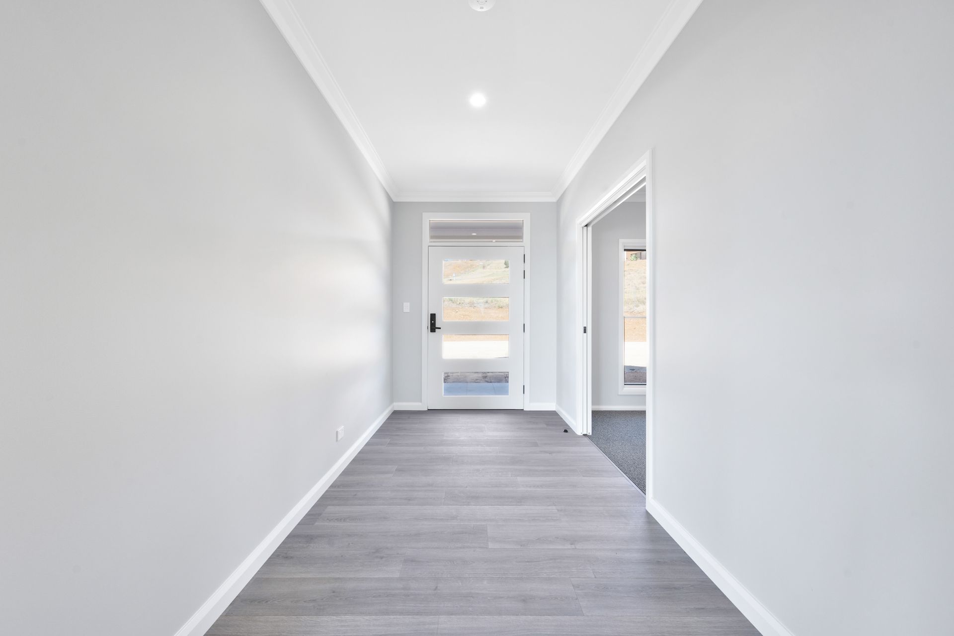 An empty hallway with a door and a window in a house.