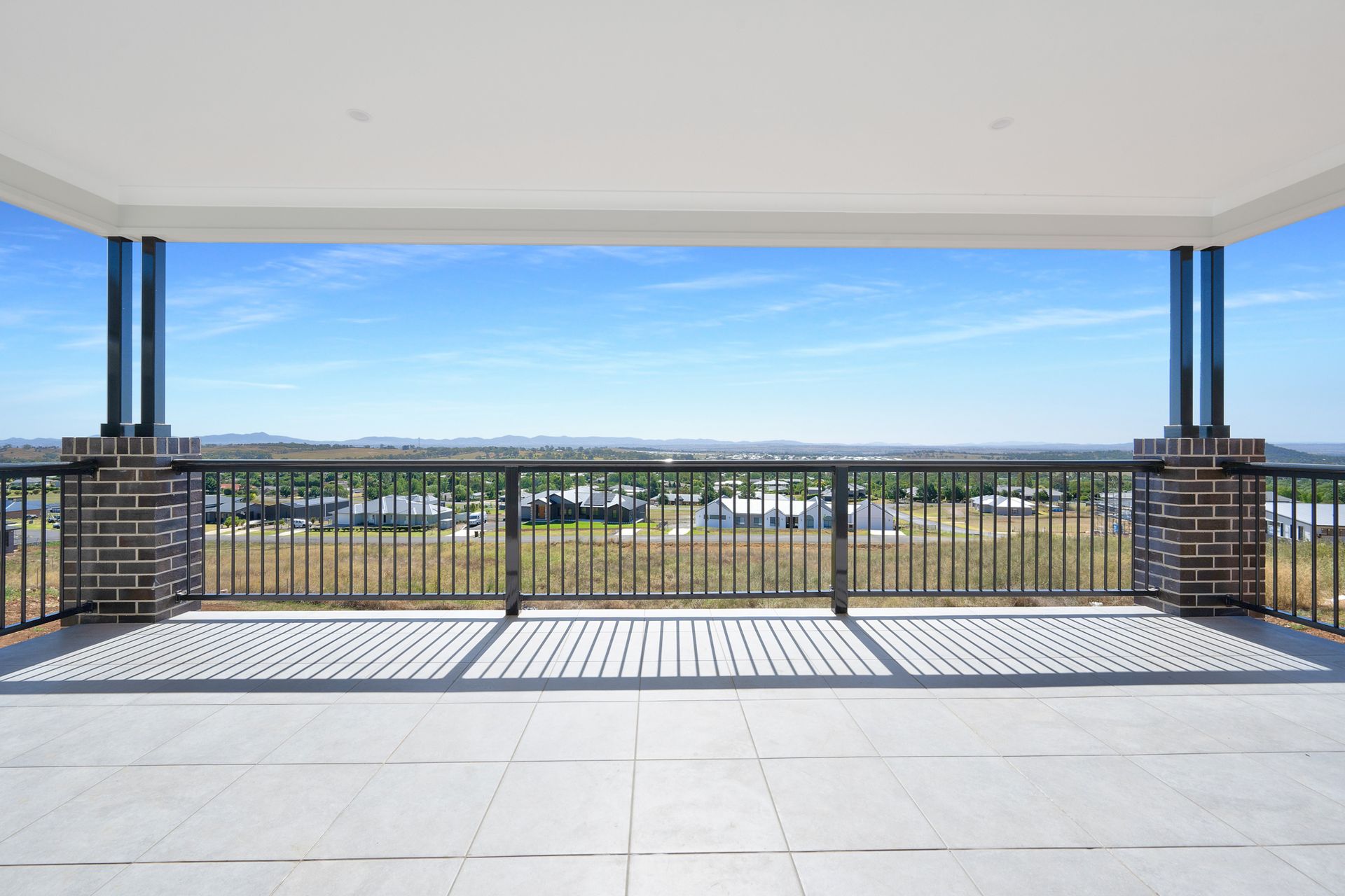An empty balcony with a view of a city and a fence.