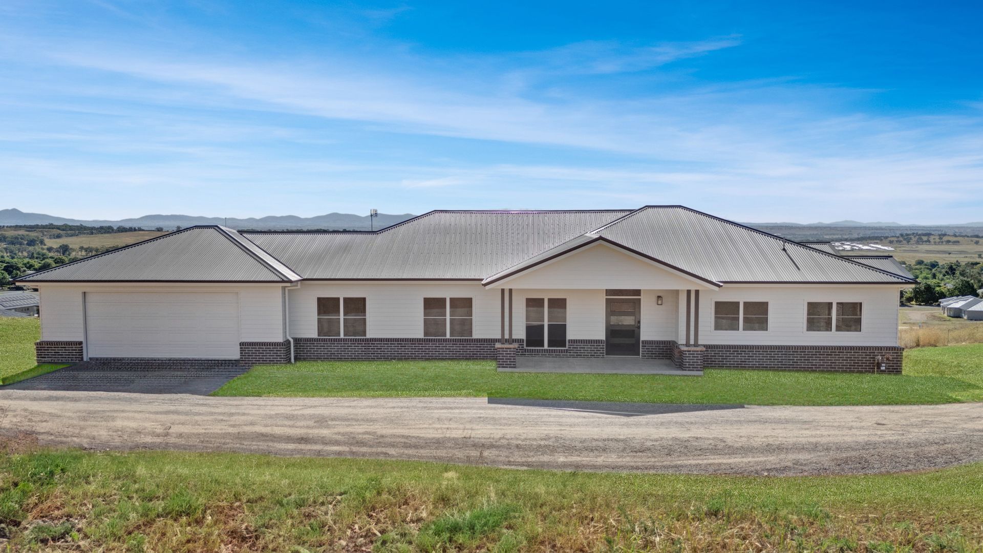 A large white house is sitting in the middle of a grassy field.
