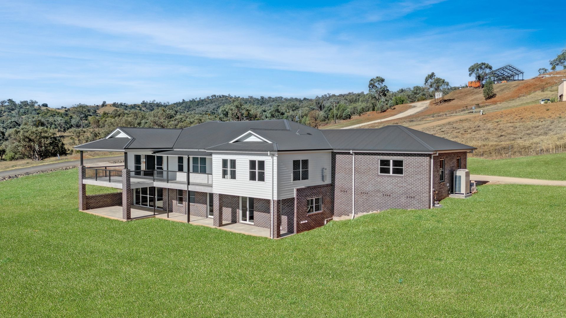 A large house is sitting on top of a lush green hillside.