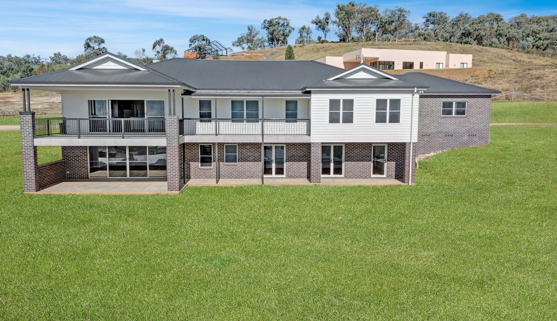 A large house is sitting on top of a lush green field.
