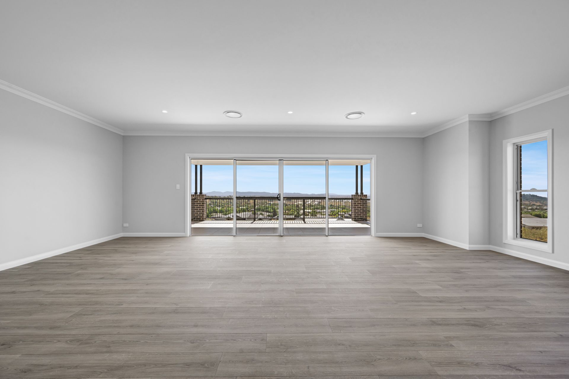 An empty living room with hardwood floors and sliding glass doors.