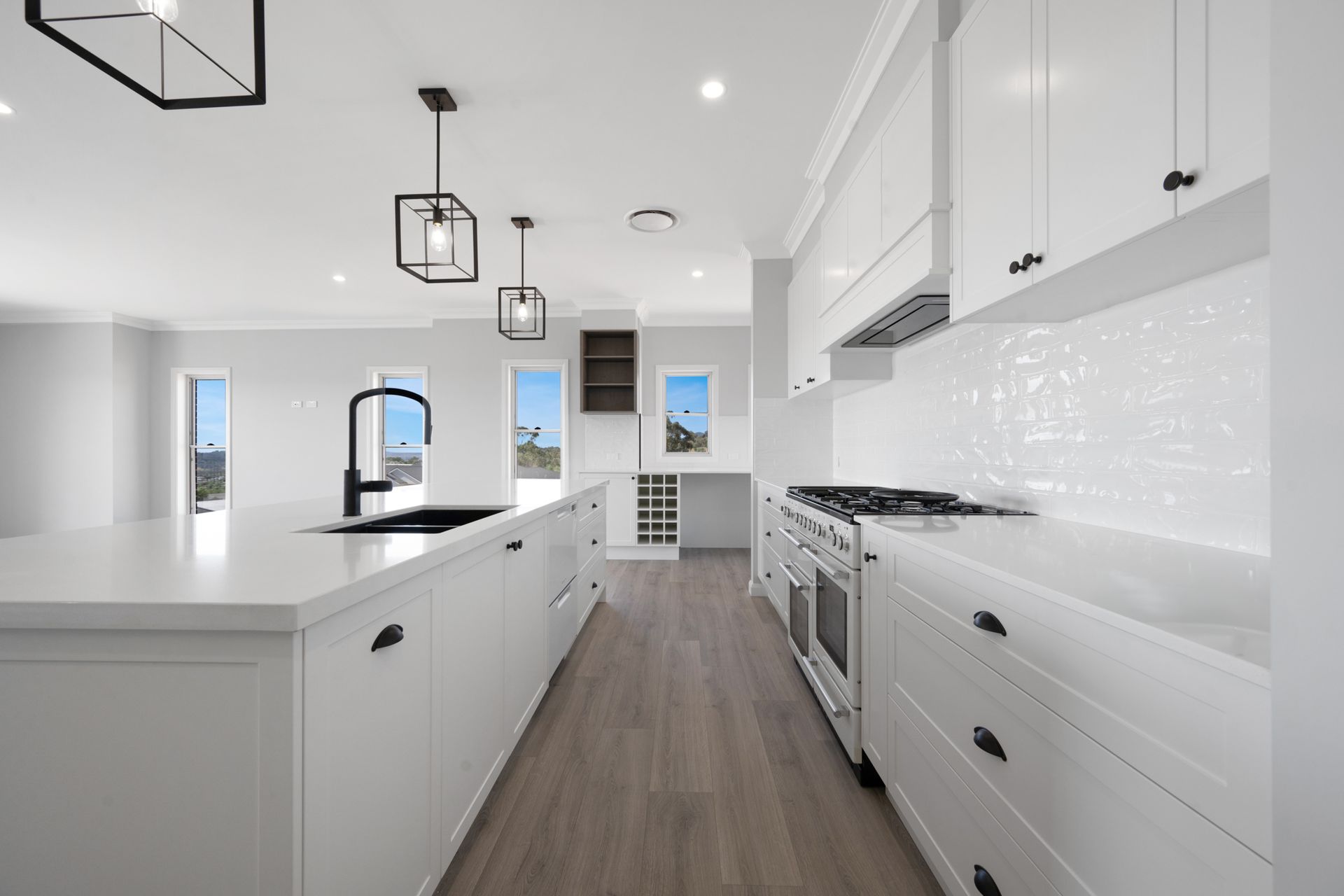 A kitchen with white cabinets and black handles