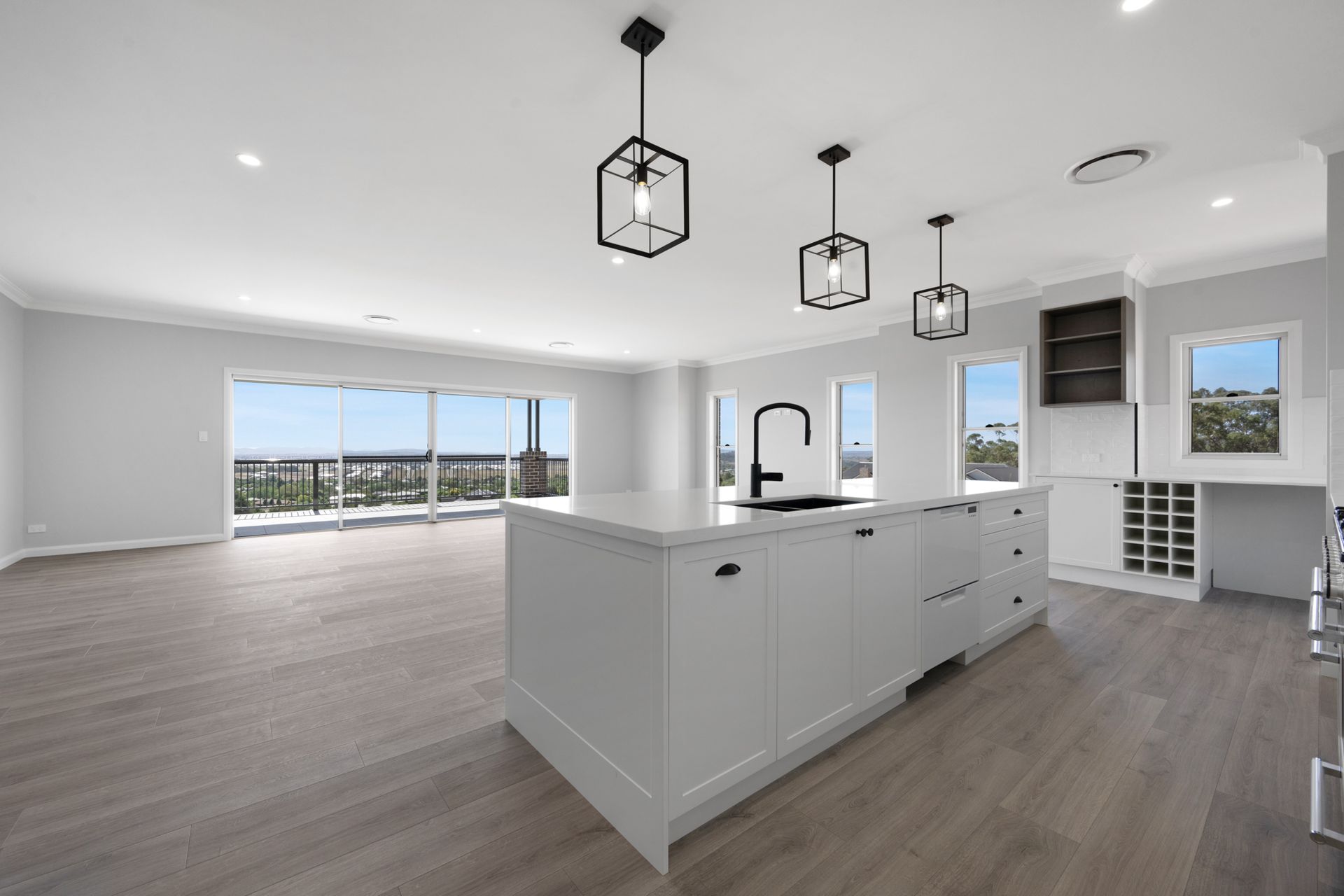 An empty kitchen with white cabinets and a large island in the middle.