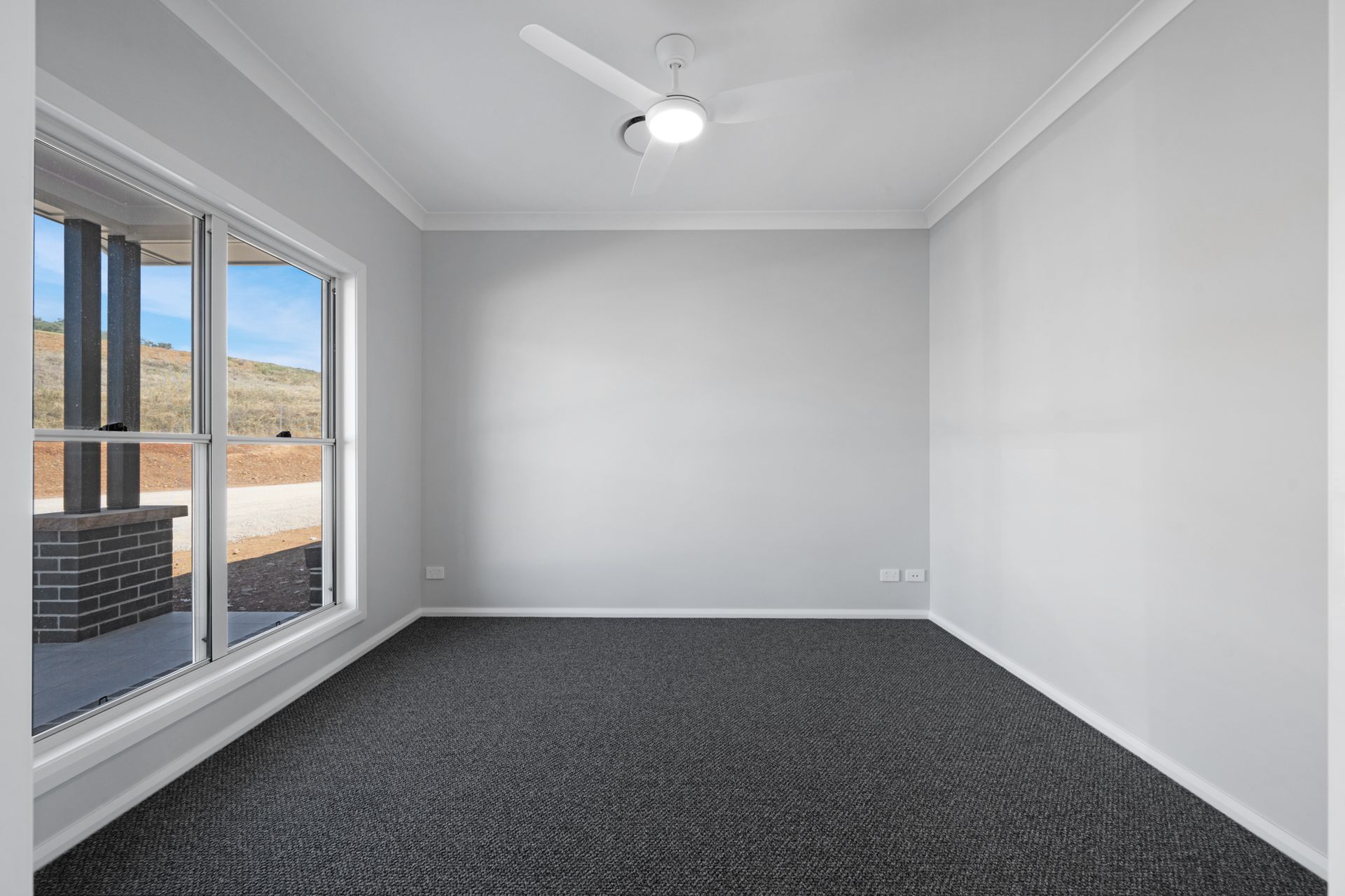 An empty room with a ceiling fan and a large window.