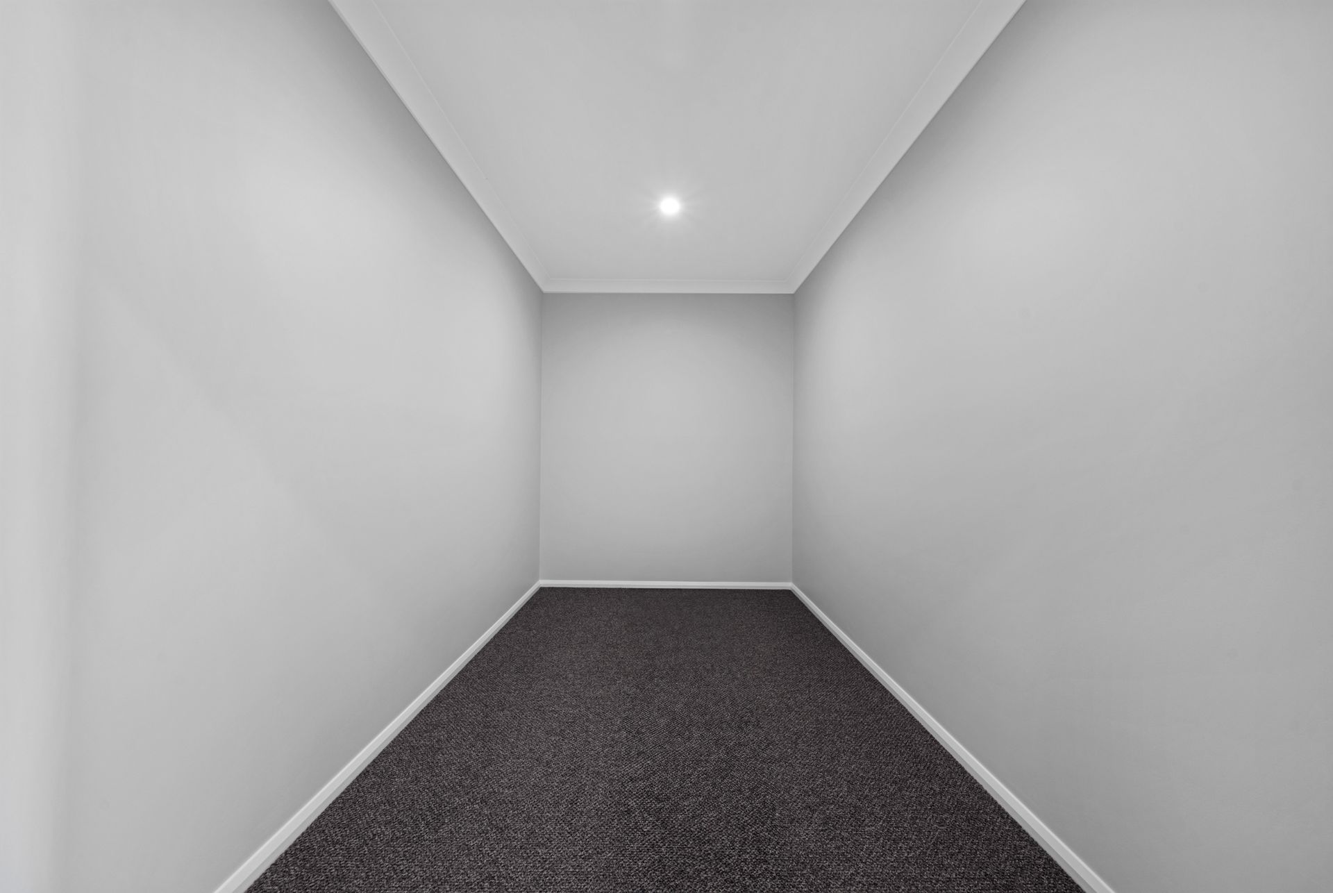An empty room with a carpeted floor and white walls.