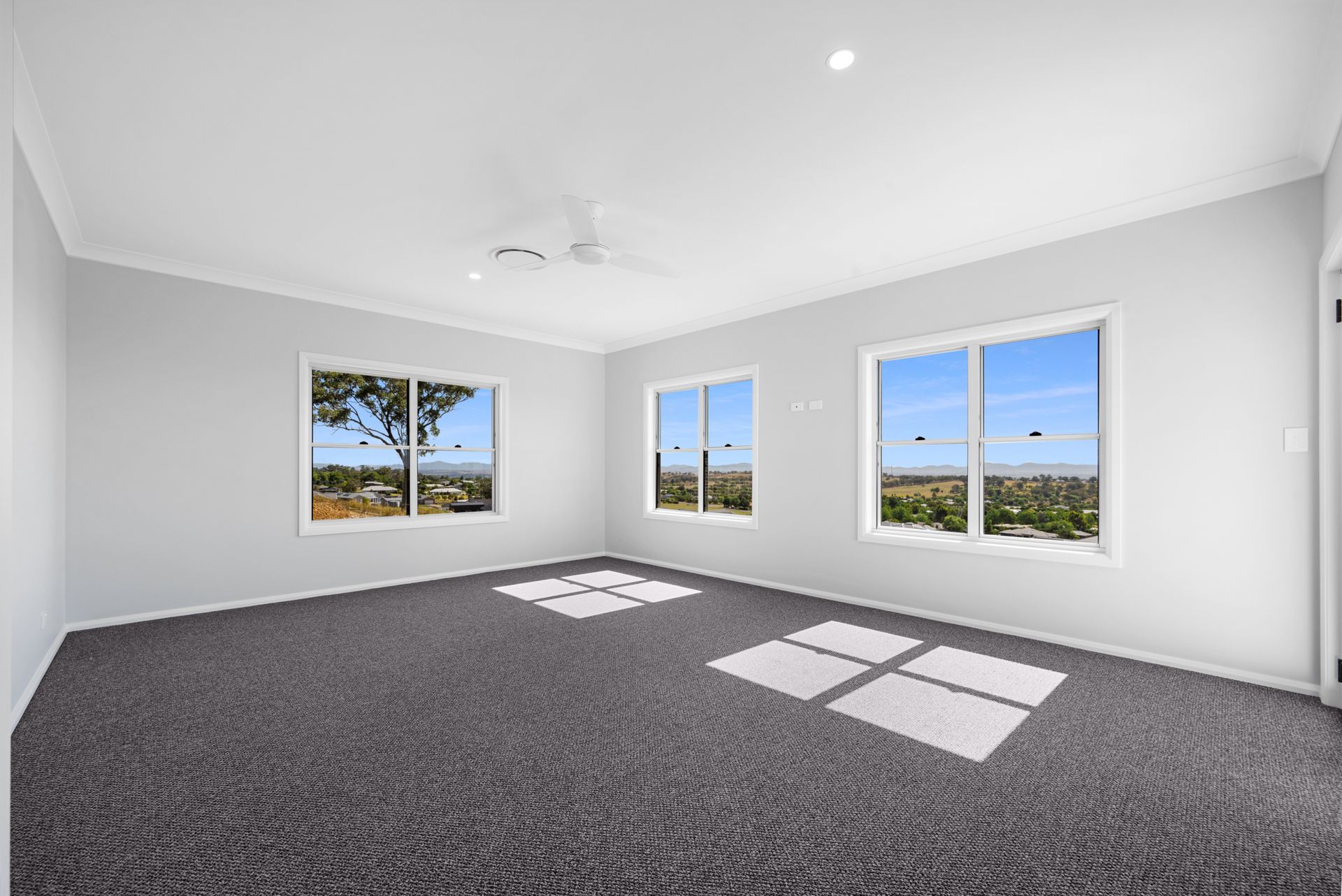 An empty room with a carpeted floor and three windows.
