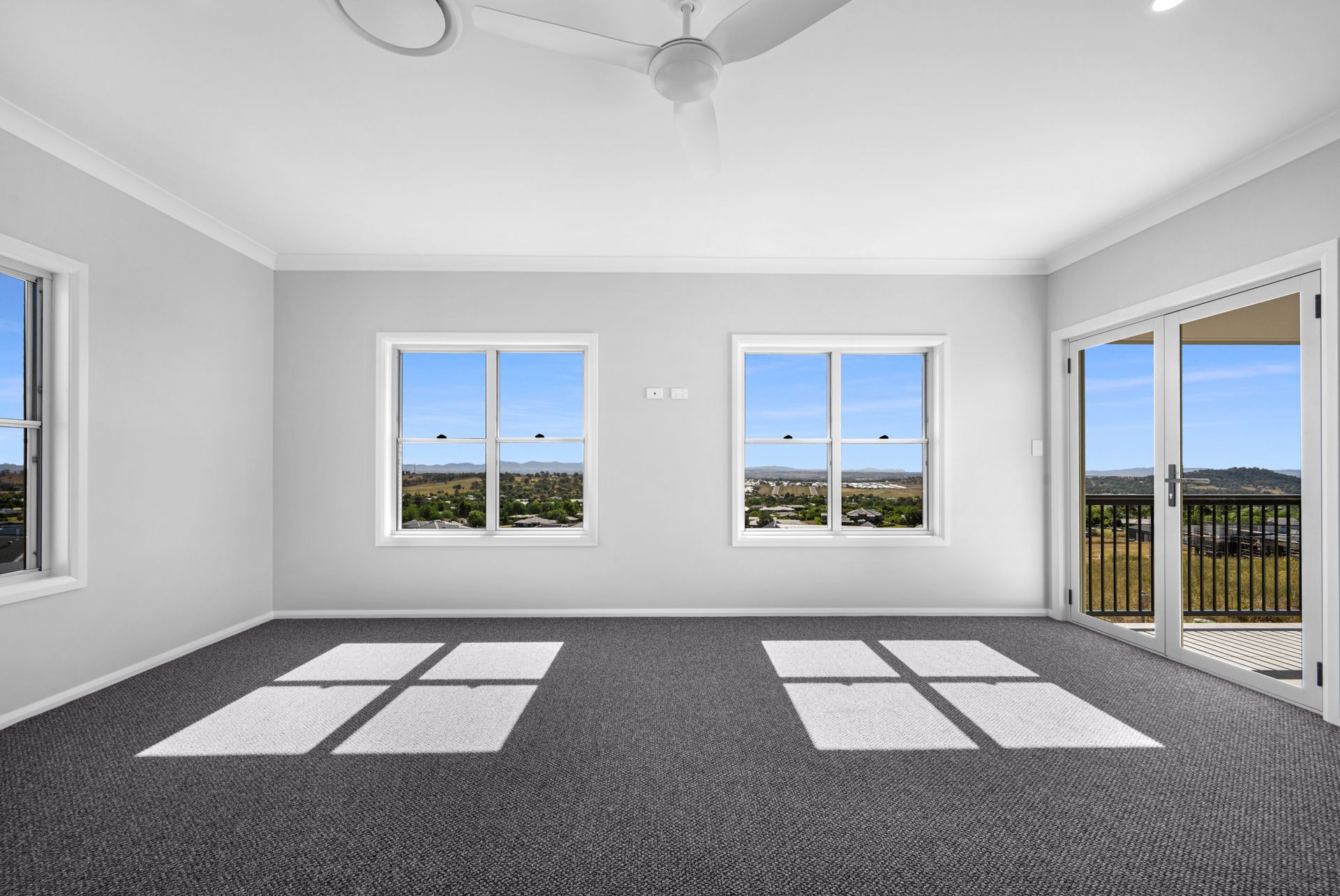 An empty room with a lot of windows and a ceiling fan.