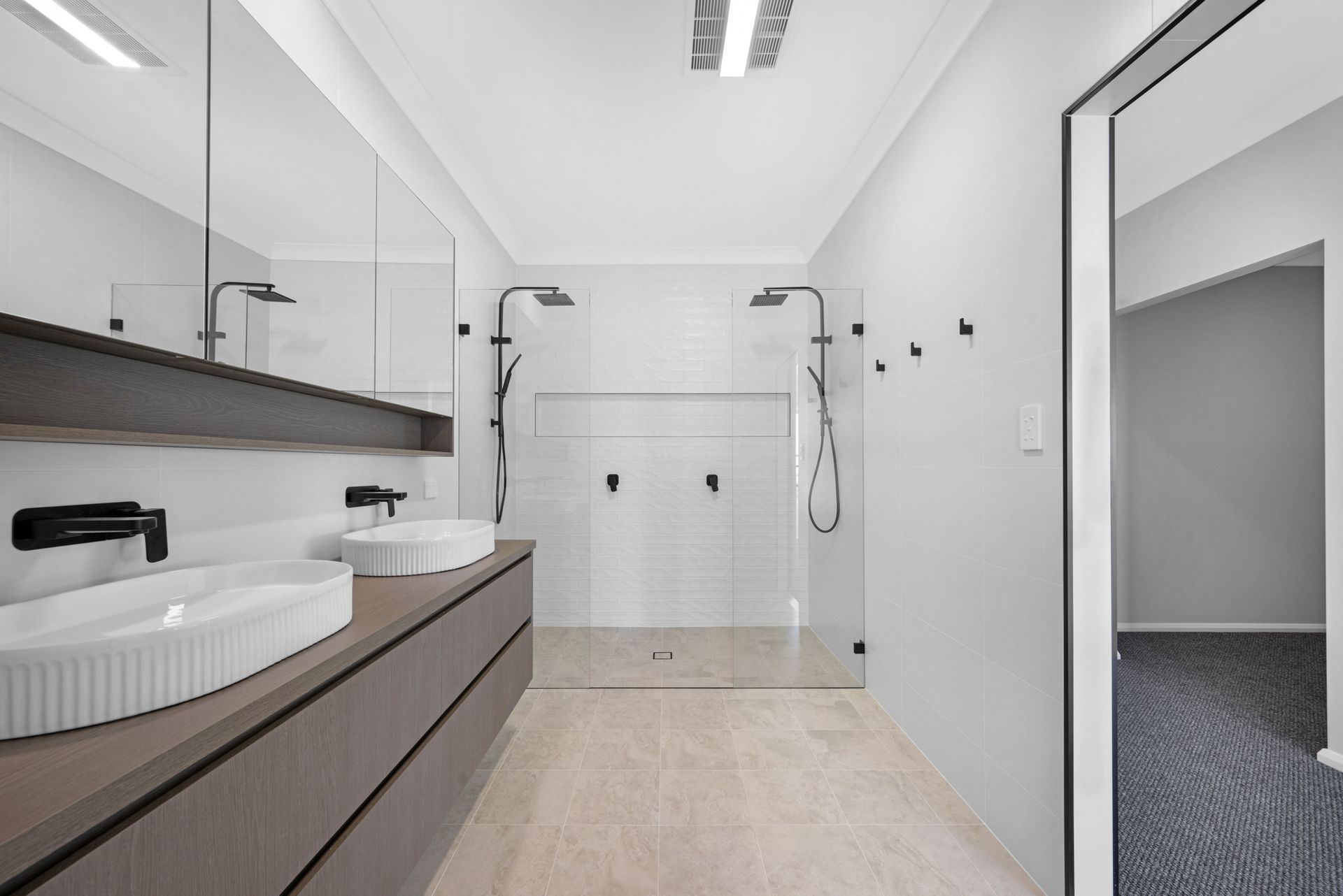 A bathroom with two sinks and a walk in shower.
