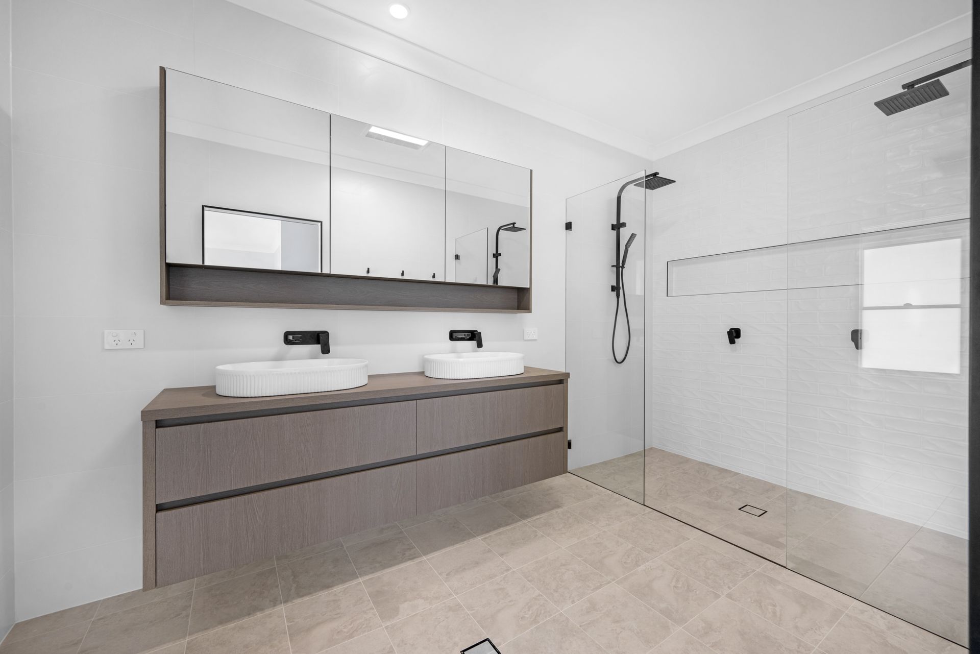 A bathroom with two sinks and a walk in shower.