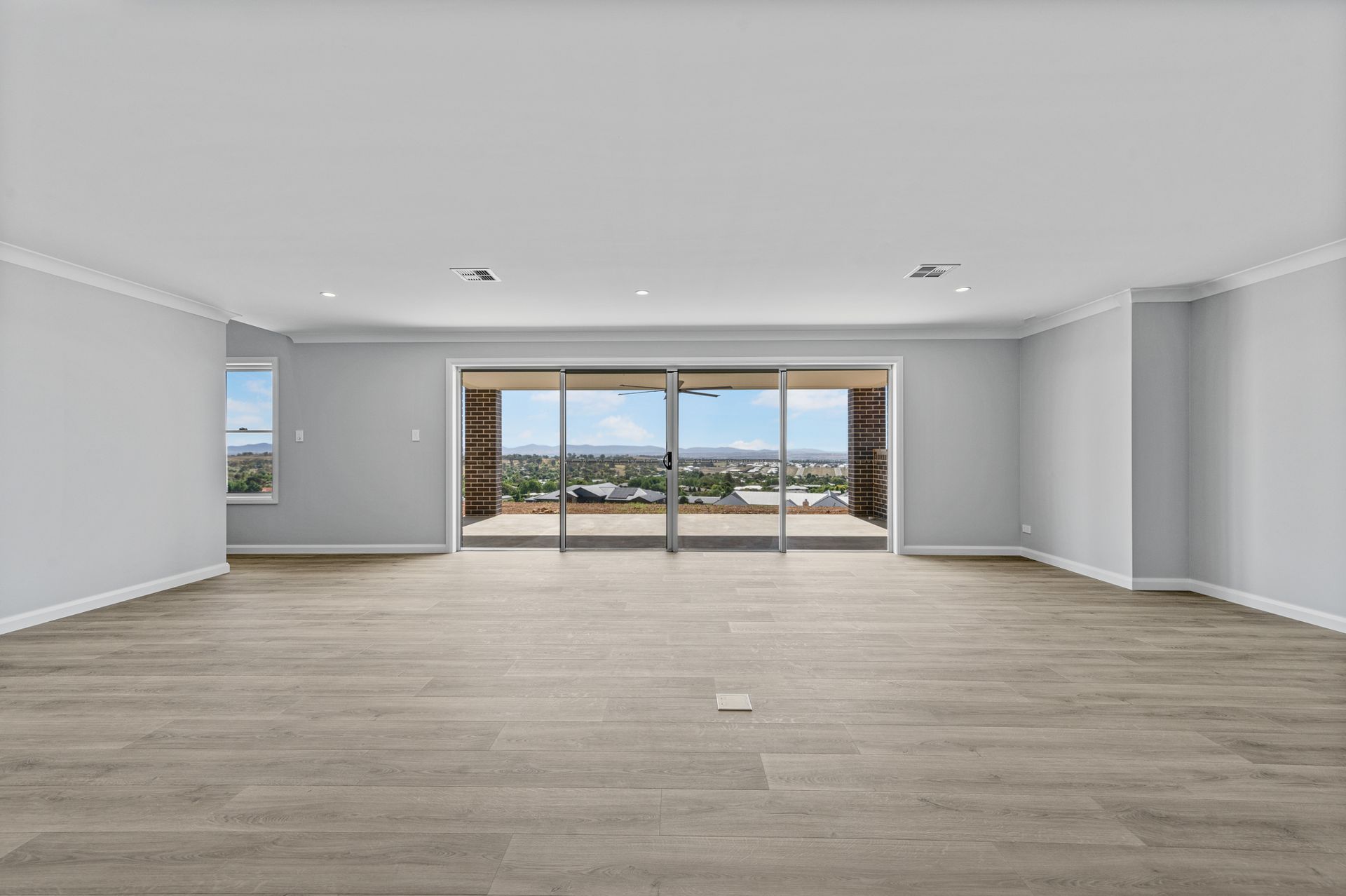 An empty living room with hardwood floors and sliding glass doors.