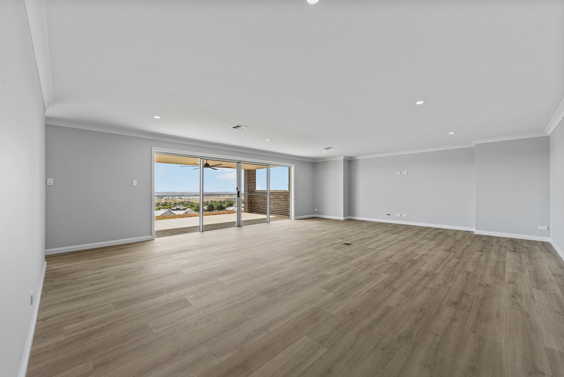 An empty living room with hardwood floors and sliding glass doors.