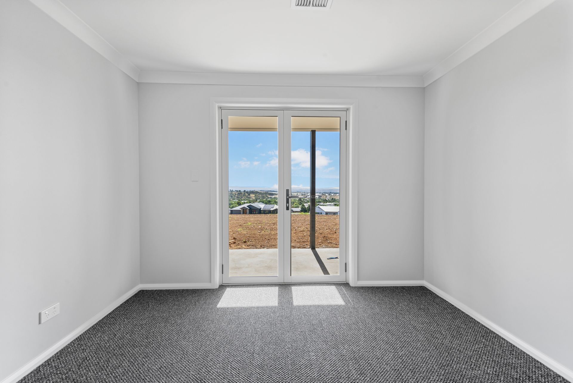 An empty room with a sliding glass door and a view of a field.