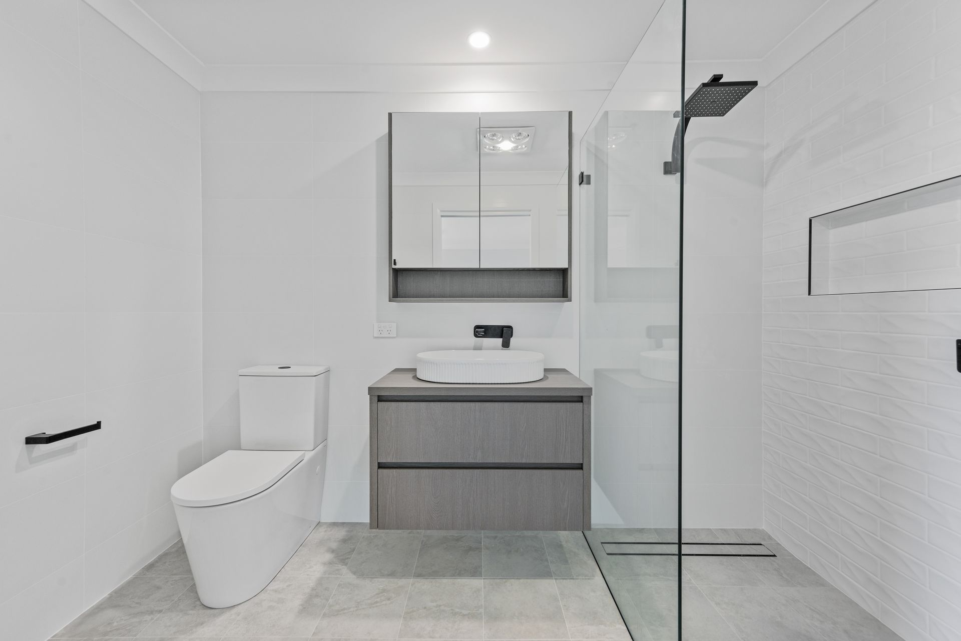 A bathroom with a toilet , sink and walk in shower.