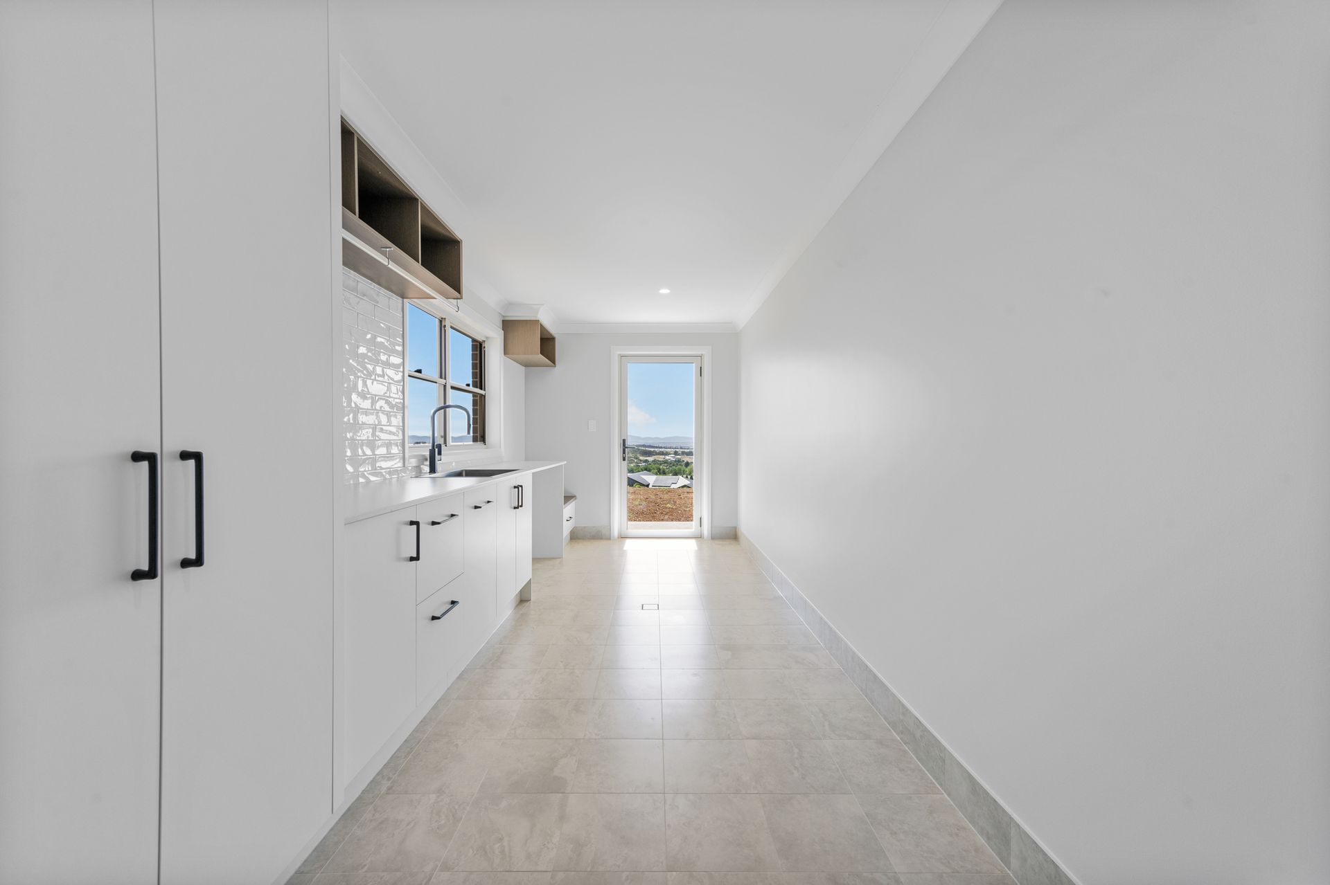 An empty kitchen with white cabinets and a large window.
