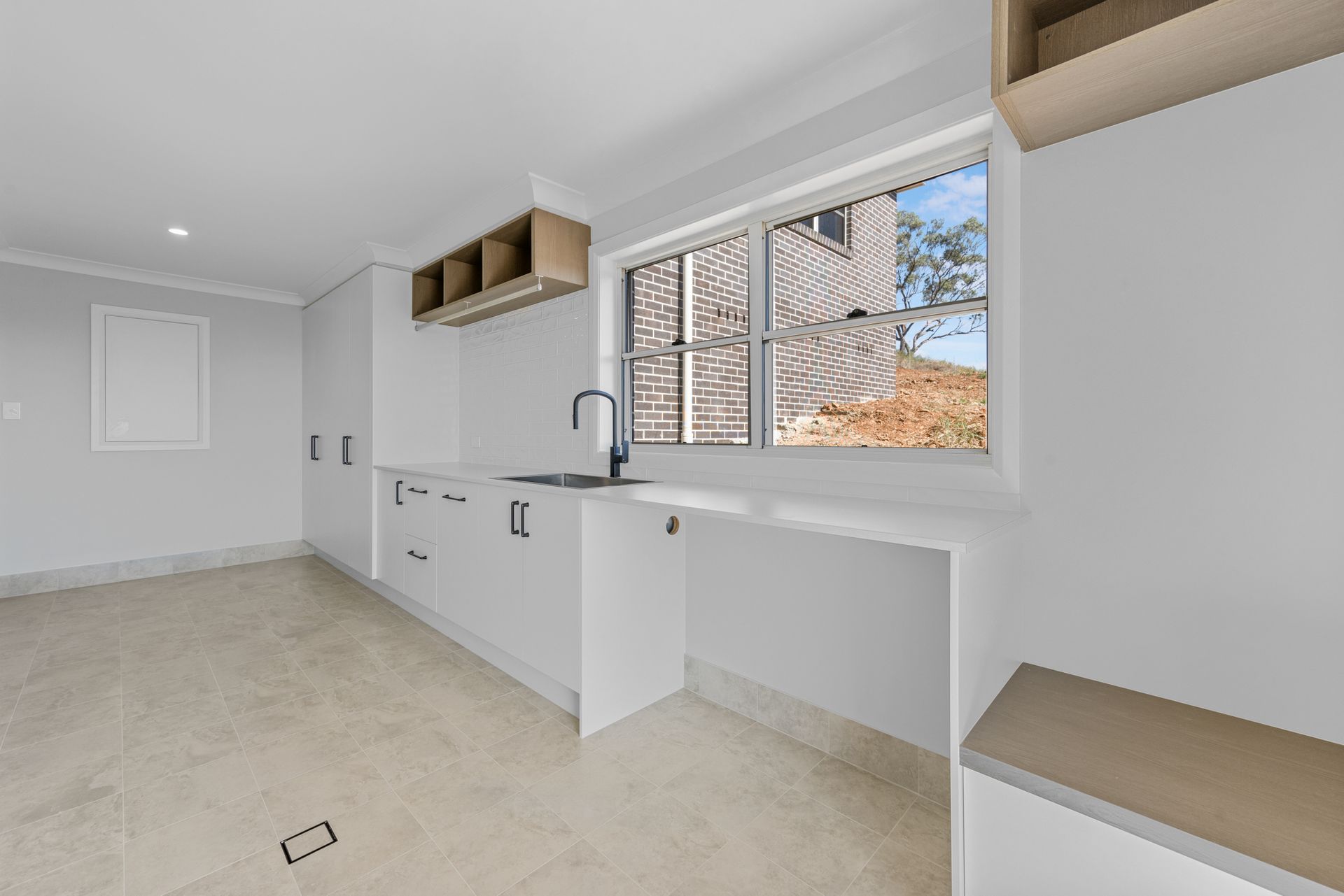 A kitchen with white cabinets , a sink , and a window.