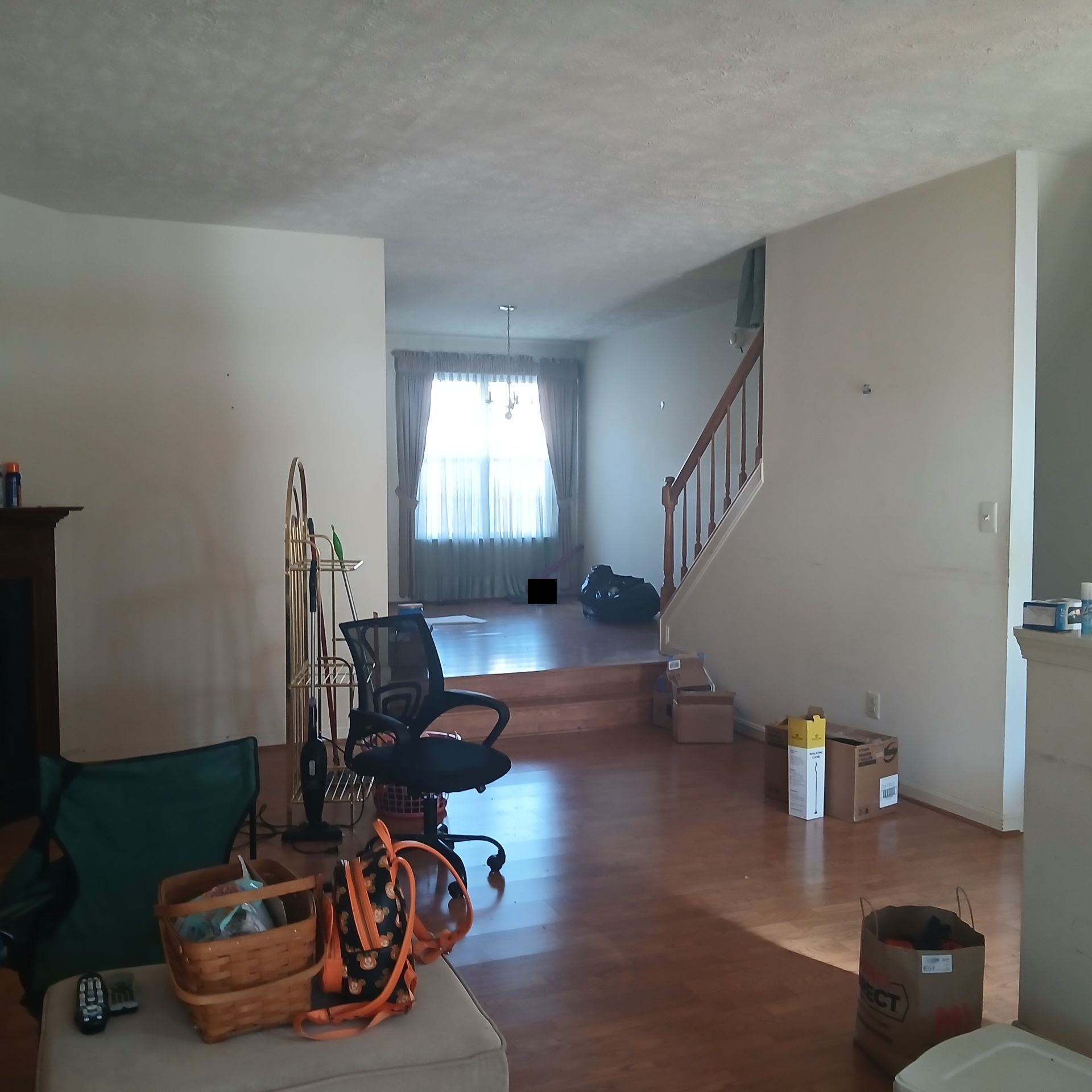 A living room with hardwood floors, a staircase, and a doorway leading to a window.