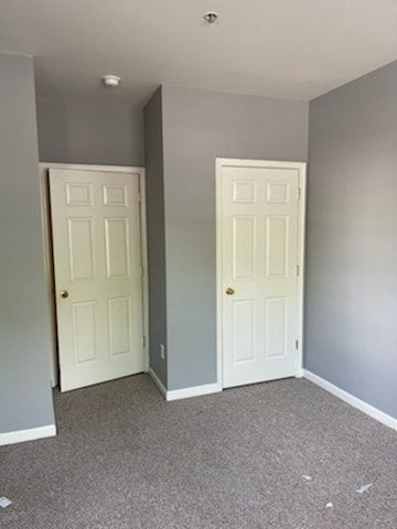 A bedroom with two doors and a carpeted floor.