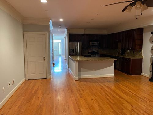 An empty kitchen with hardwood floors and a ceiling fan.