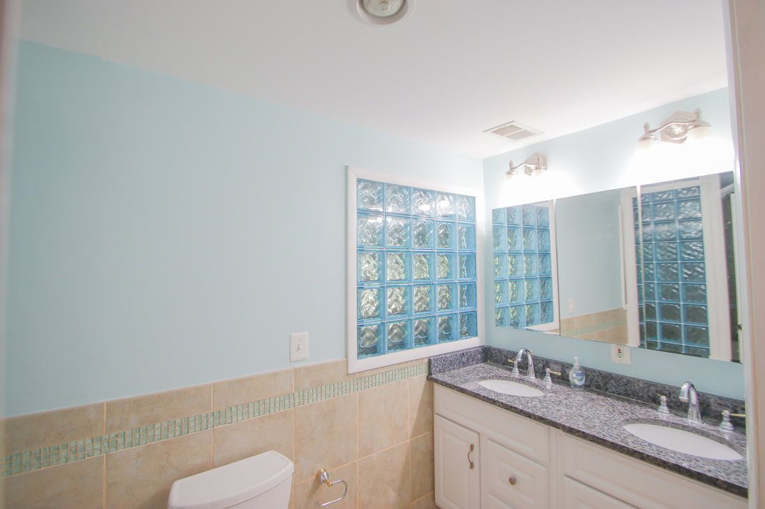 A bathroom with two sinks , a toilet and a mirror.