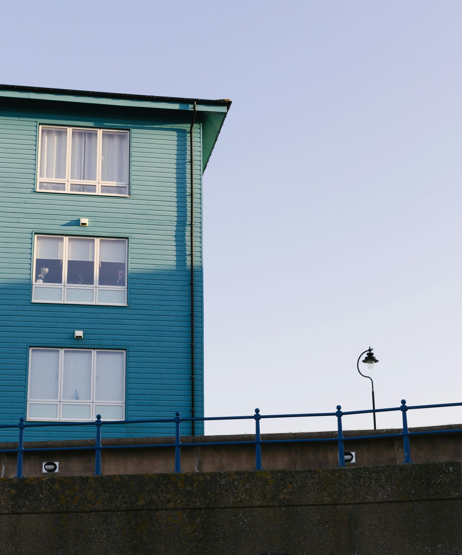 A blue building with white windows and a blue railing