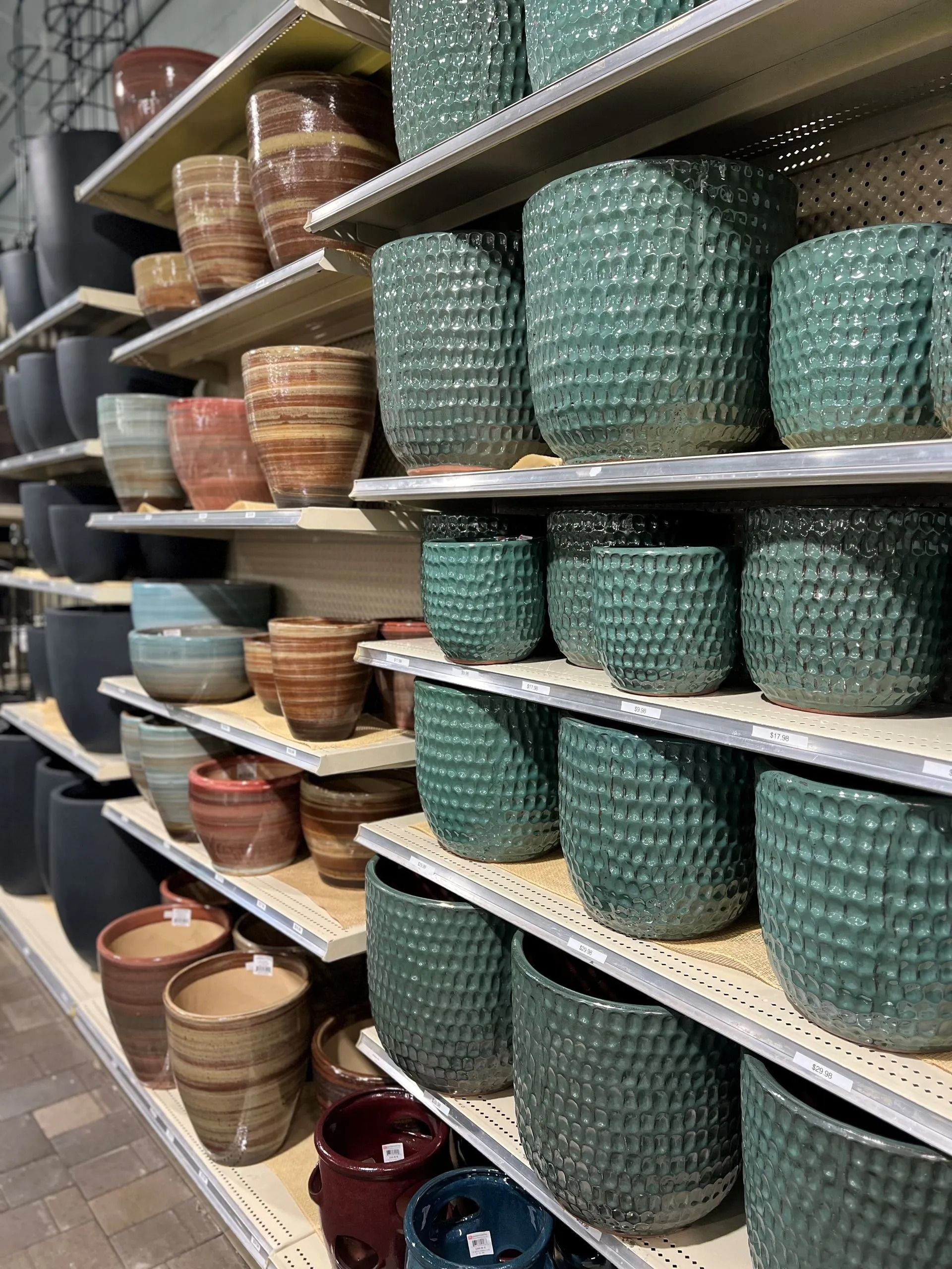 Shelves displaying various ceramic flower pots in teal, brown, and black.