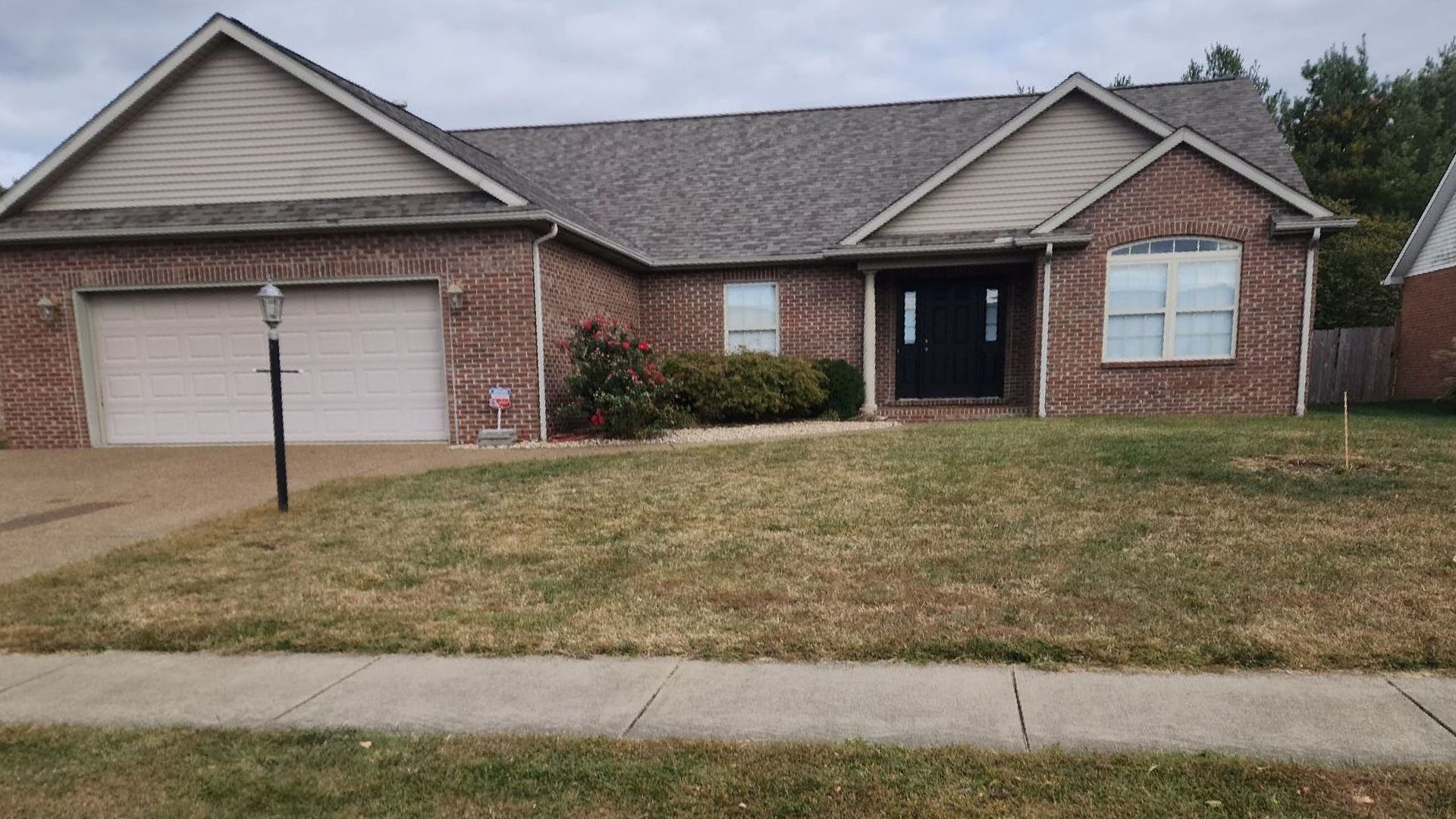 A brick house with a gray roof and white garage doors