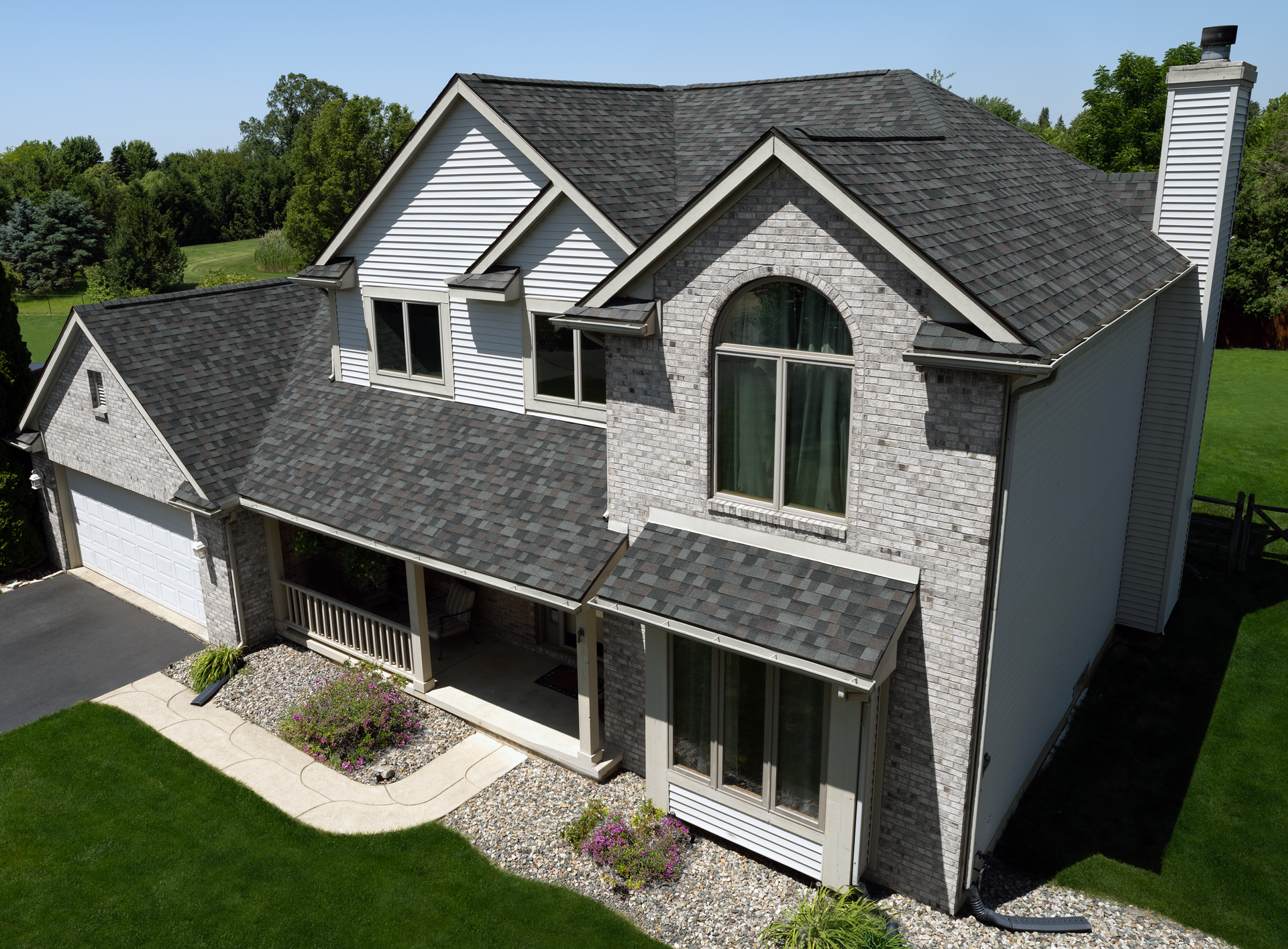 An aerial view of a large brick house with a gray roof