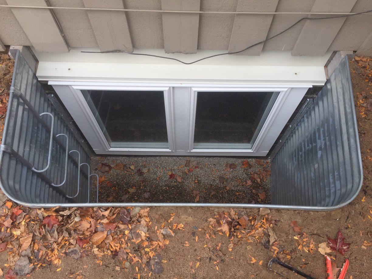 A window in the ground next to a house.