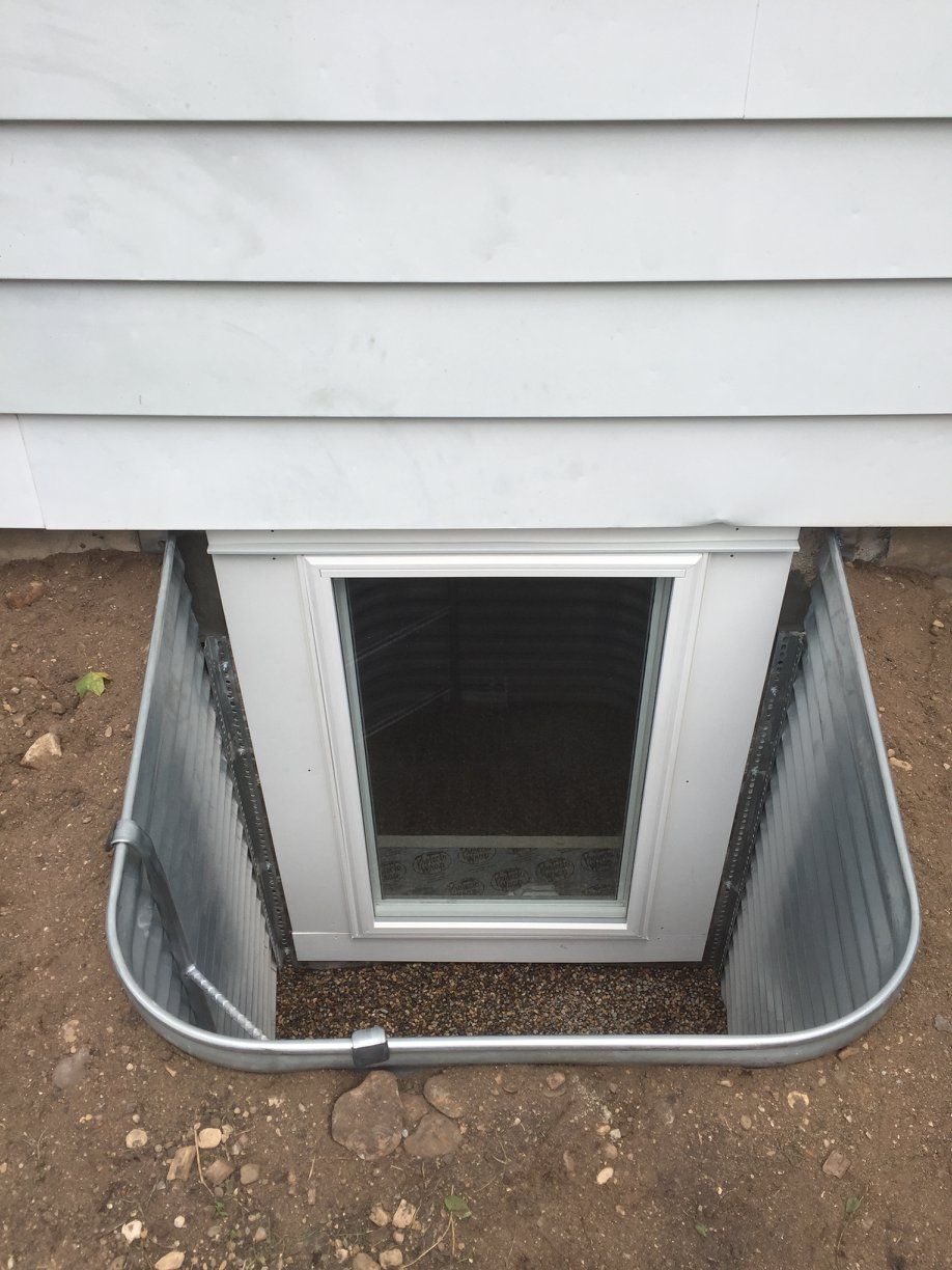 A window in a basement with a dog door.