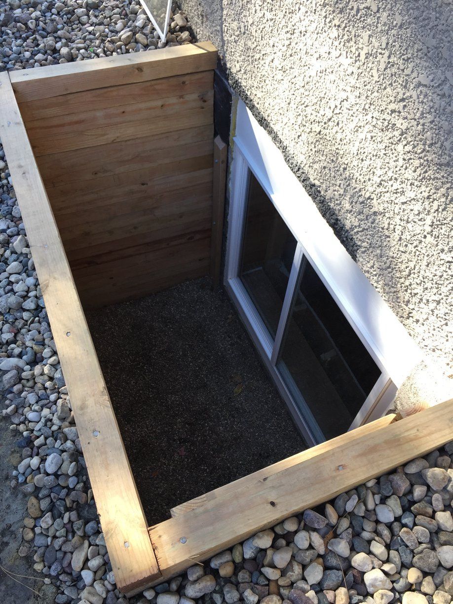 A window in a basement with a wooden frame around it