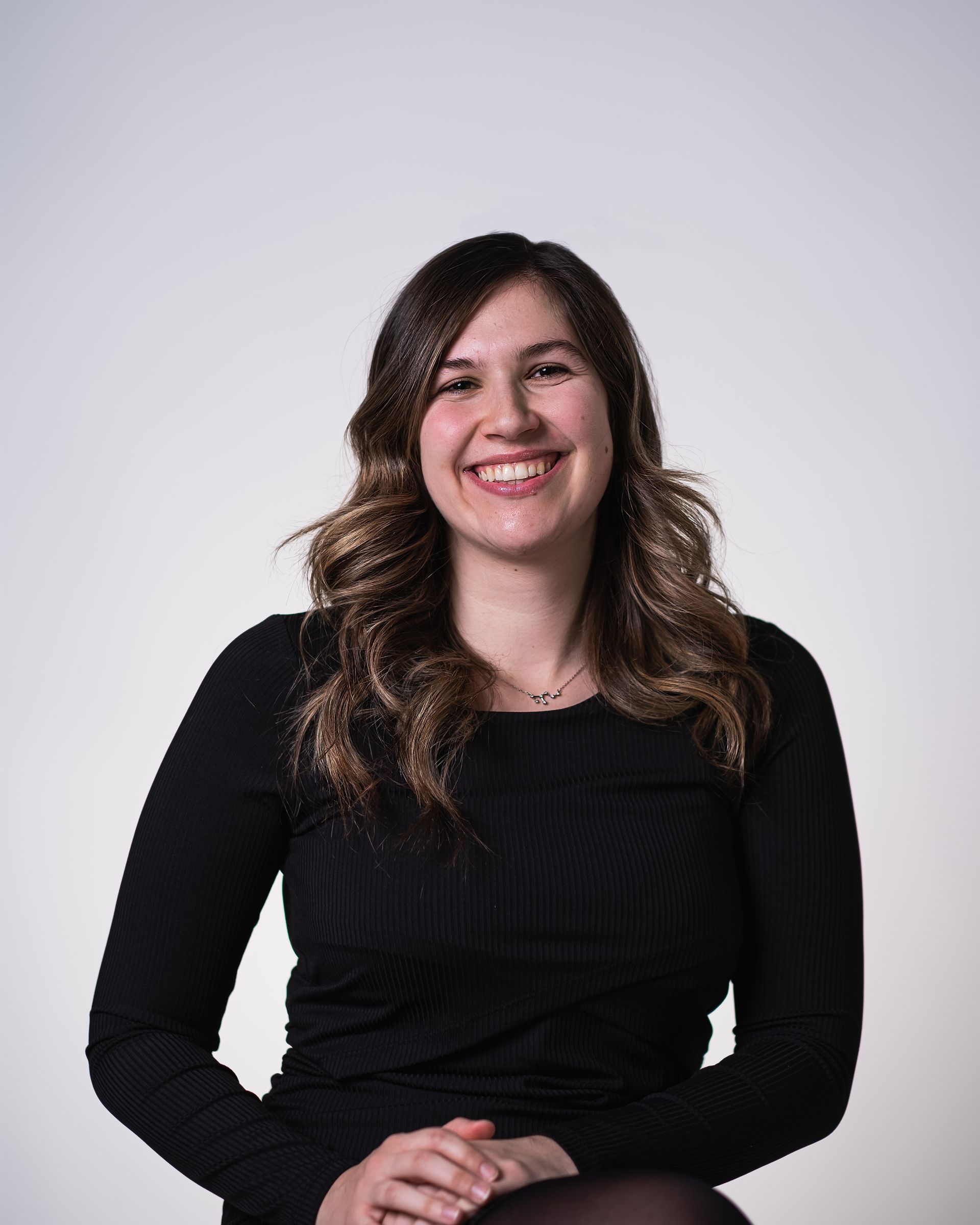 Une femme vêtue d'un pull noir sourit à la caméra