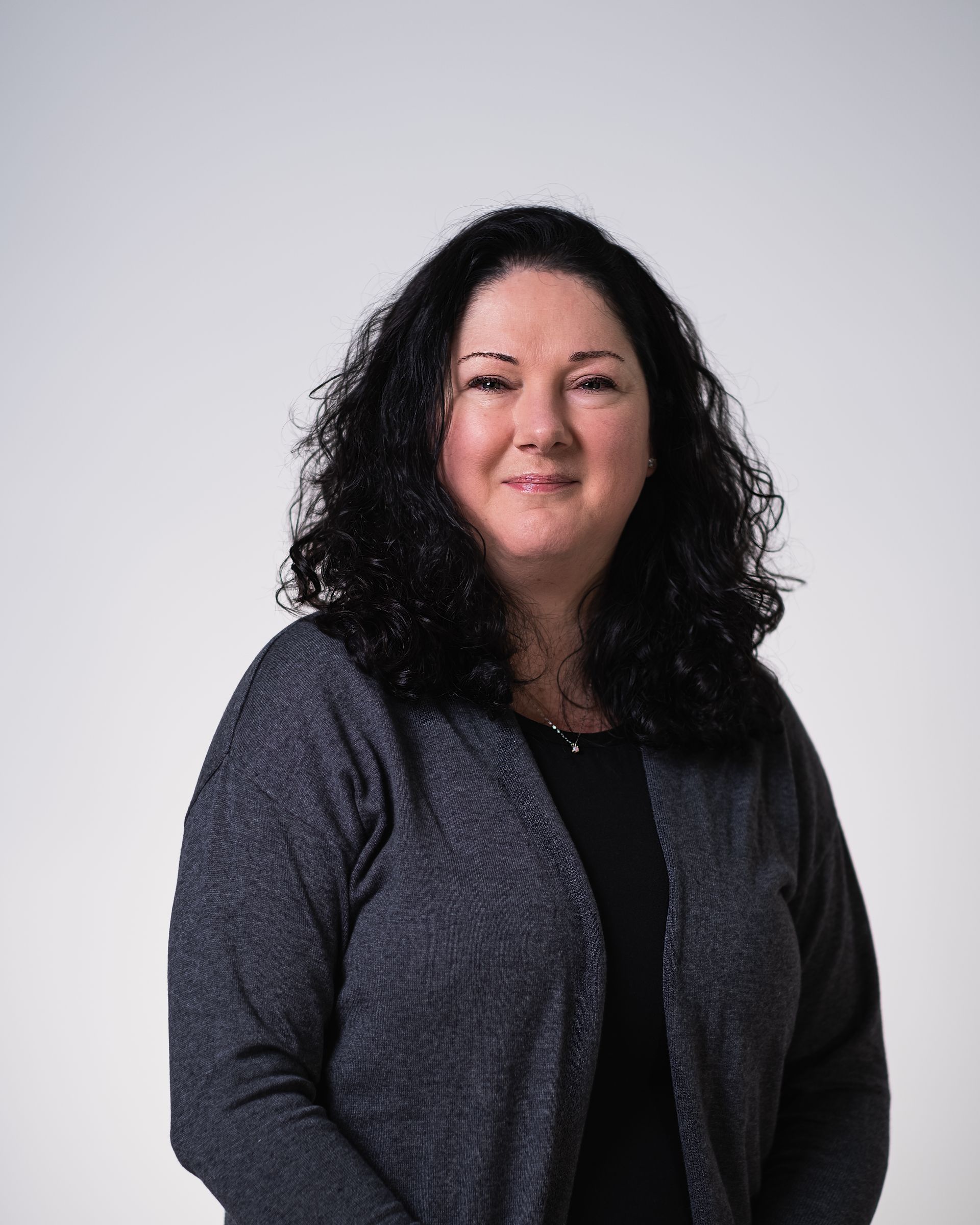 Une femme aux cheveux bouclés porte un cardigan gris
