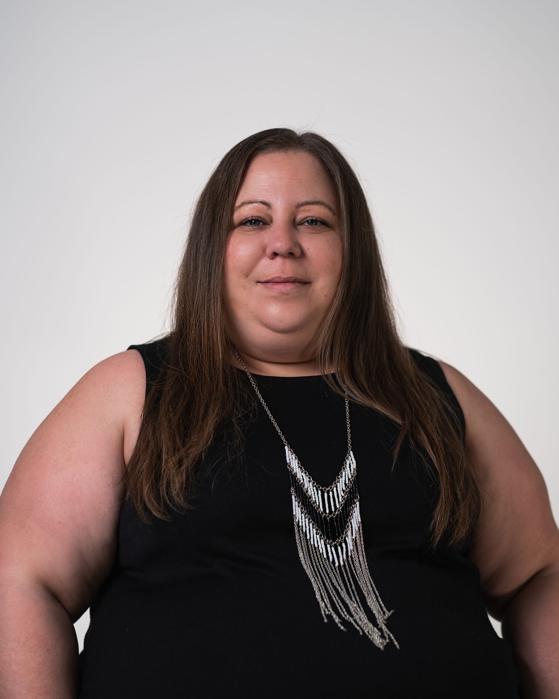 Une femme porte une robe noire et un collier en argent.