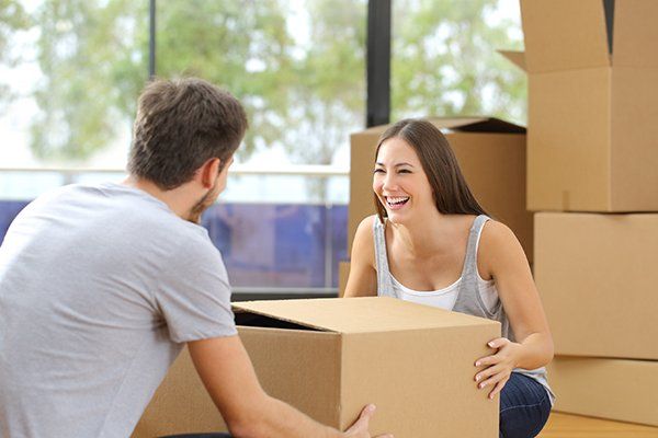 A couple laughs as they unpack boxes.