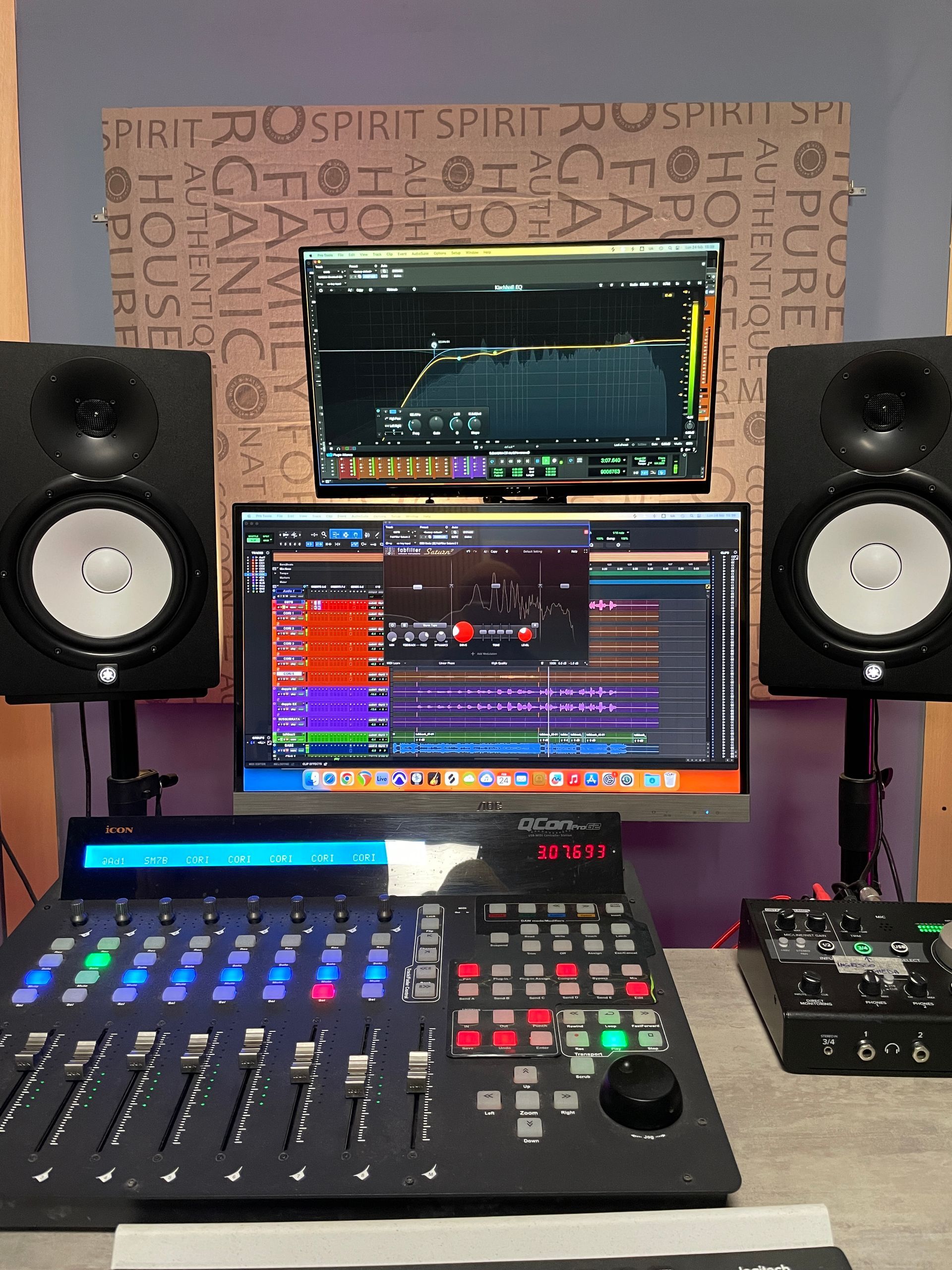 Configurazione dello studio di registrazione con console di mixaggio, monitor per computer che visualizzano il software di editing audio e monitor da studio.