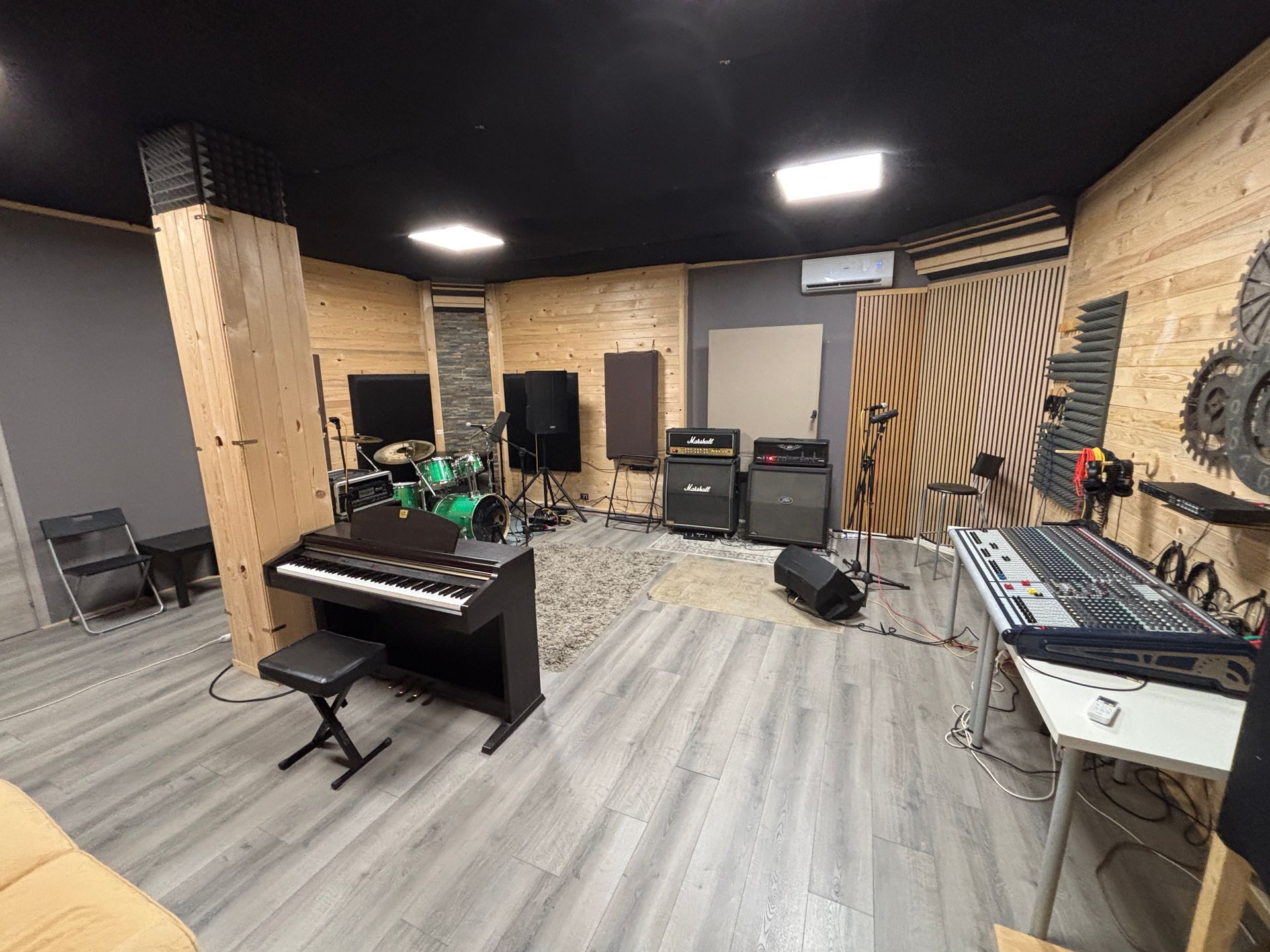 Interno di uno studio musicale con strumenti, altoparlanti e insonorizzazione, dotato di pianoforte e console di mixaggio.
