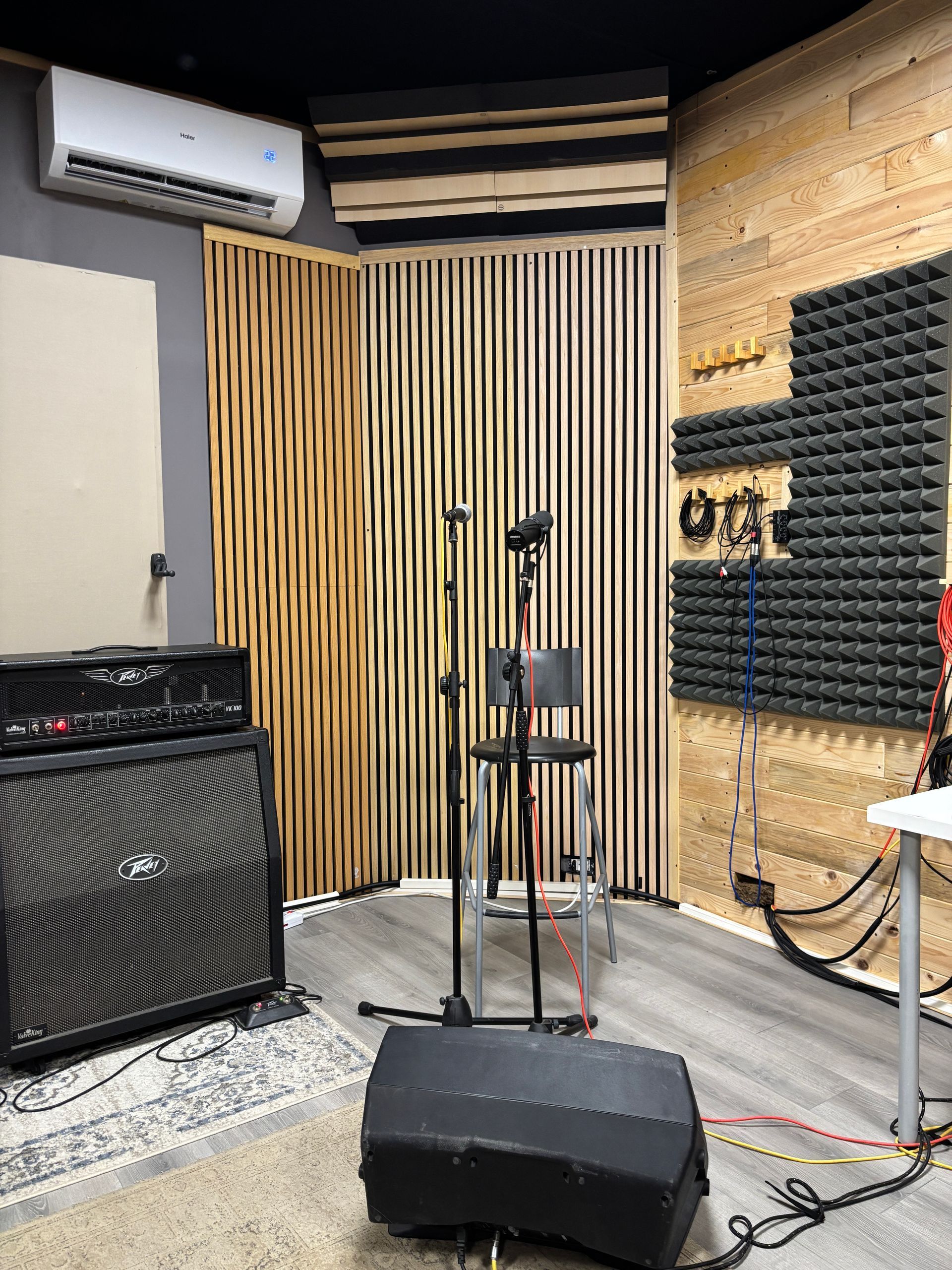 Interno di uno studio di registrazione, con supporti per microfono, pannelli acustici, altoparlanti e un amplificatore.