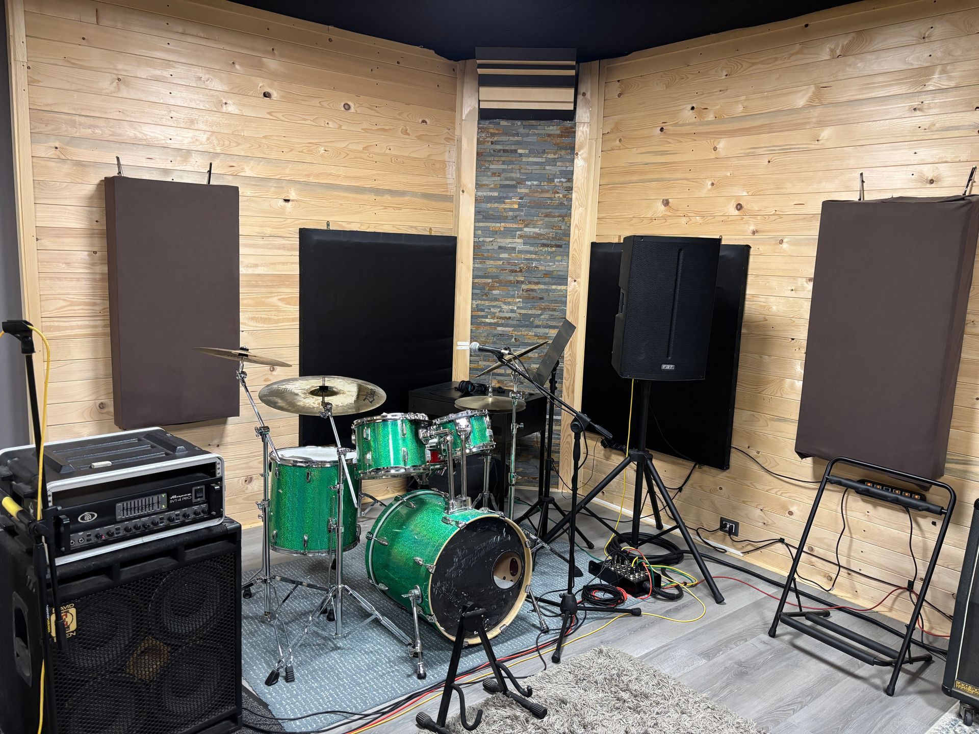Batteria in una stanza insonorizzata con pannelli acustici, altoparlanti e apparecchiature di registrazione.