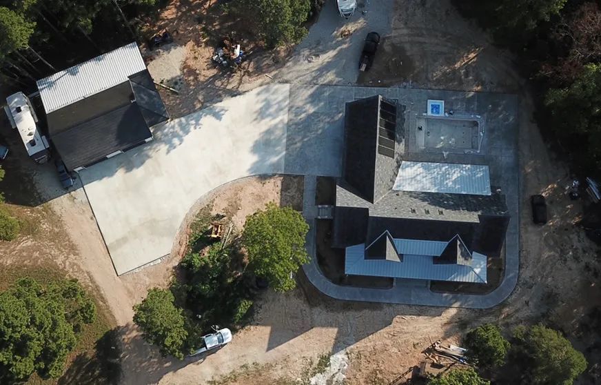 An aerial view of a house in the middle of a forest.