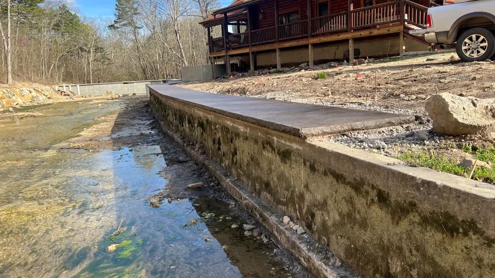 A white truck is parked in front of a house next to a river.