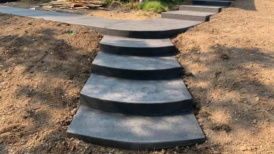 A set of concrete stairs leading up to a dirt hill.