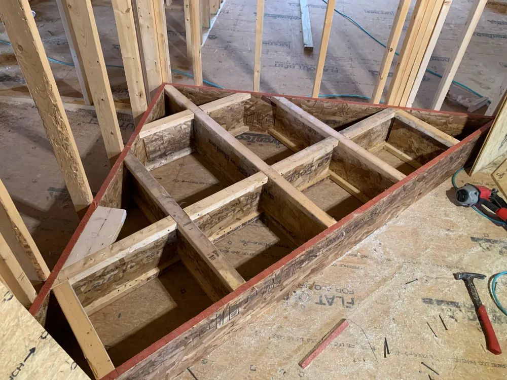 A wooden staircase is being built in a house under construction.
