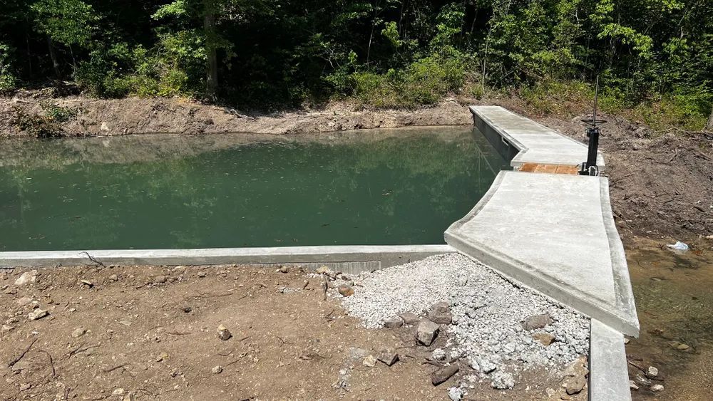 A concrete dock is sitting next to a body of water.